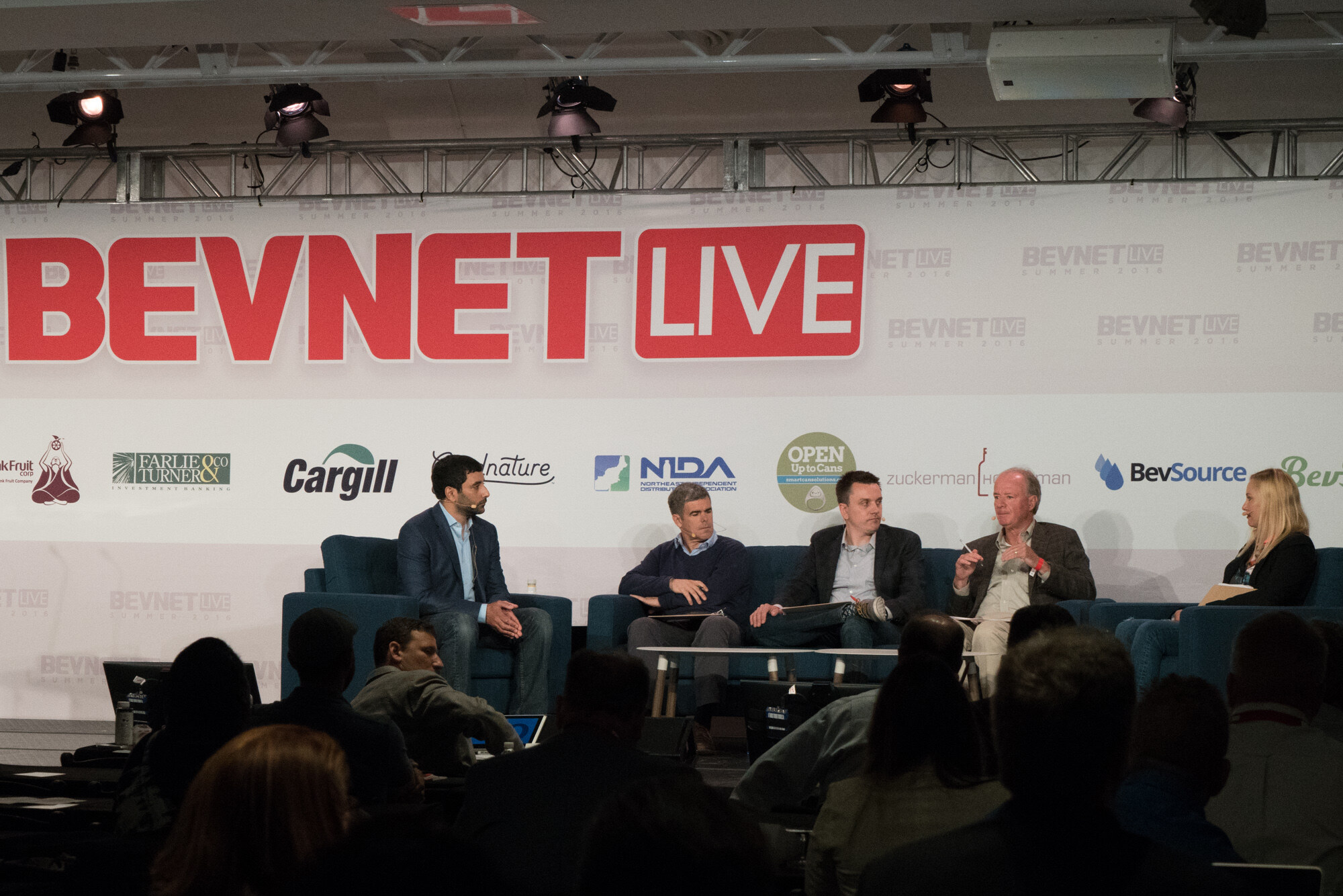 View over the heads of the audience toward a moderator and four panelists on blue sofas under a red BevNET Live sign and a row of sponsor logos including Cargill, NIDA and BevSource.