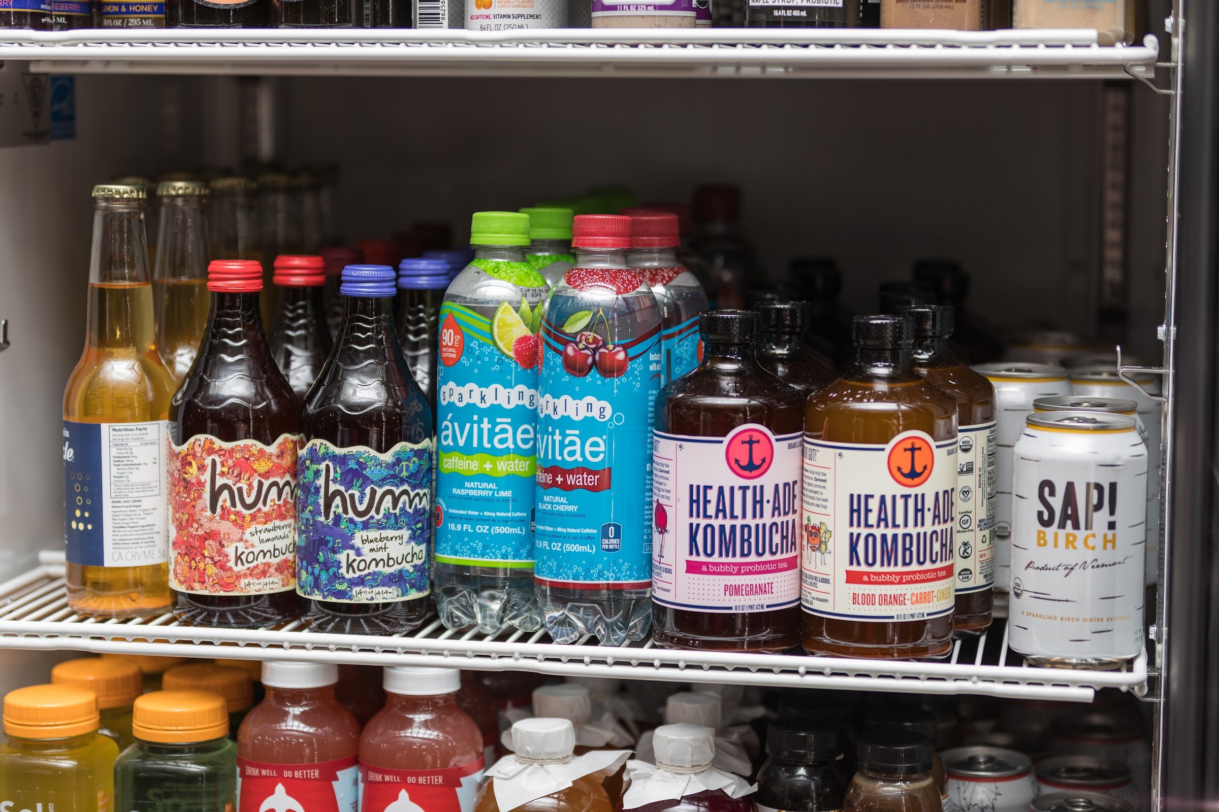Cooler shelves holding humm kombucha, Avitae sparkling water, Health-Ade kombucha and Sap! Birch cans.