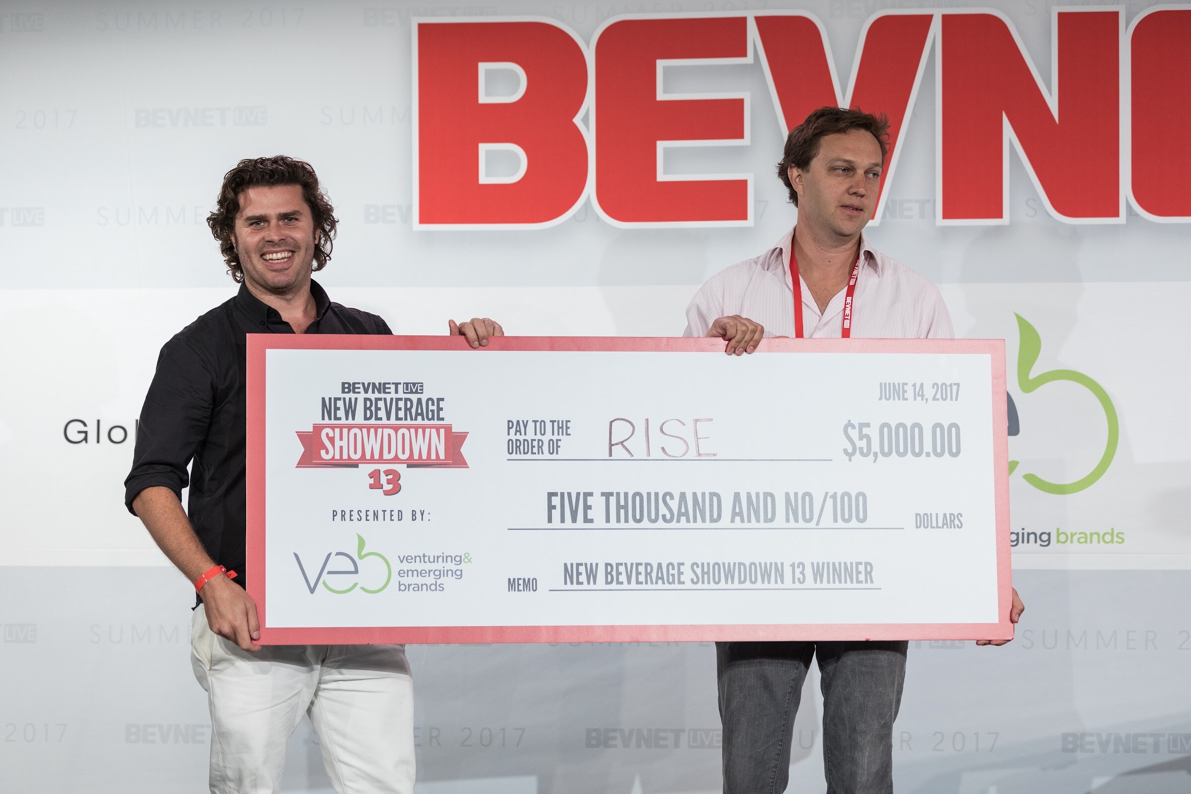 Two men holding an oversized check reading Pay to the order of RISE, $5,000.00, memo New Beverage Showdown 13 winner, dated June 14, 2017, presented by VEB.