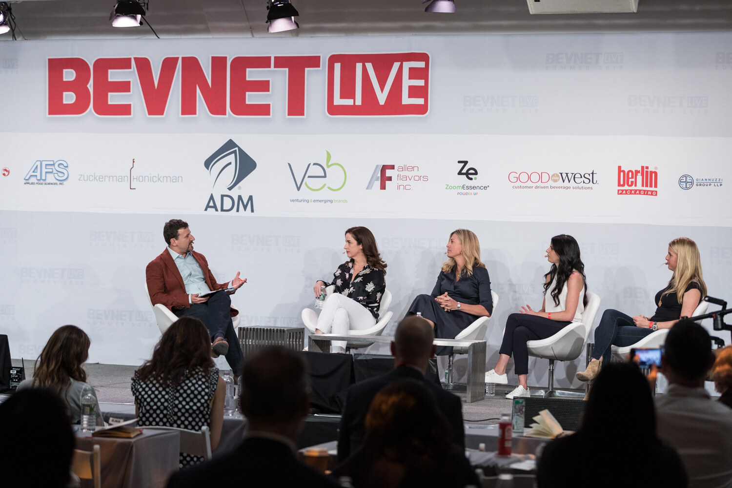 Wide view of a moderator and four women seated in white chairs on stage in front of the BevNET Live backdrop.