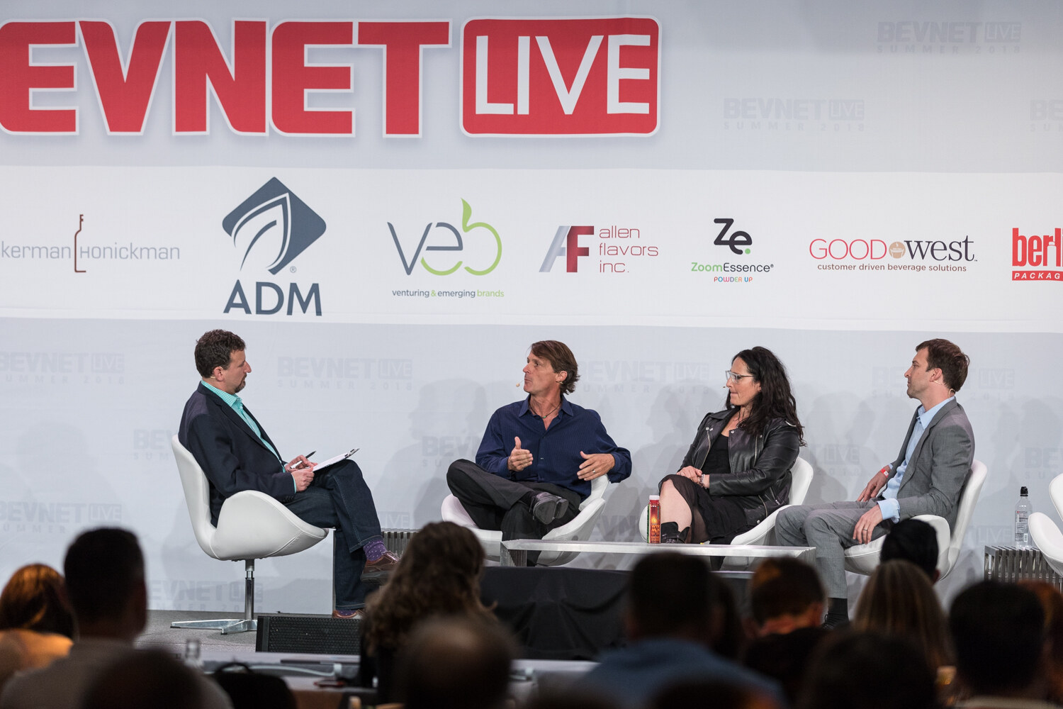 Wide view of a moderator and three panelists seated on stage in front of the BevNET Live sign and sponsor logos.