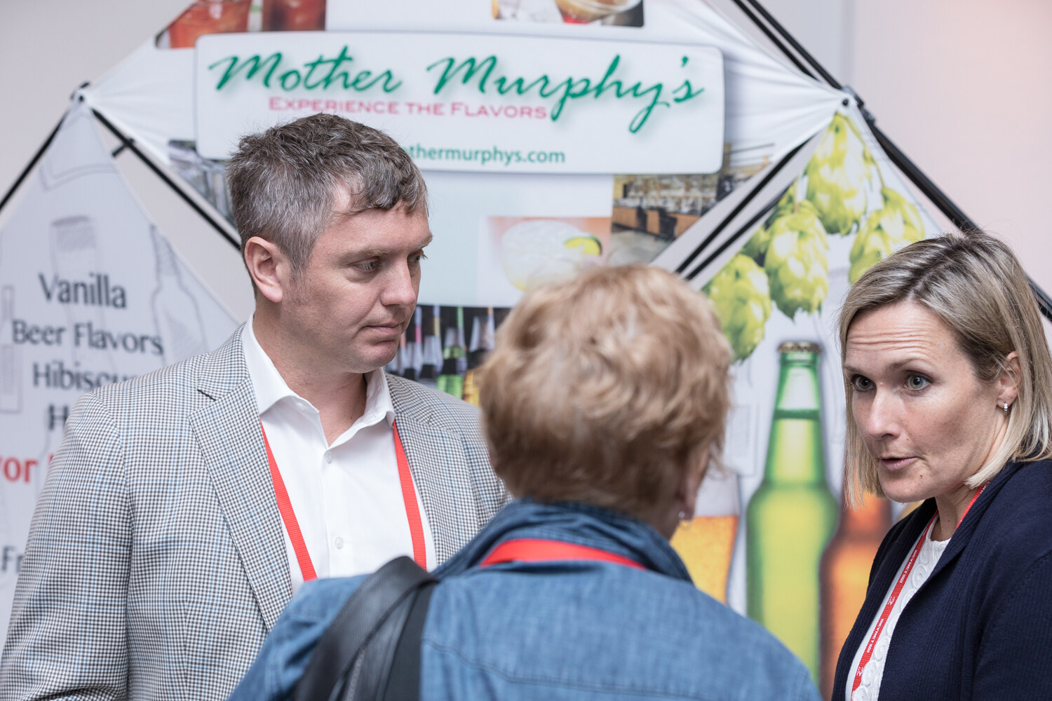 A man in a gray blazer and a woman in a navy jacket stand in front of a Mother Murphy's flavor display.