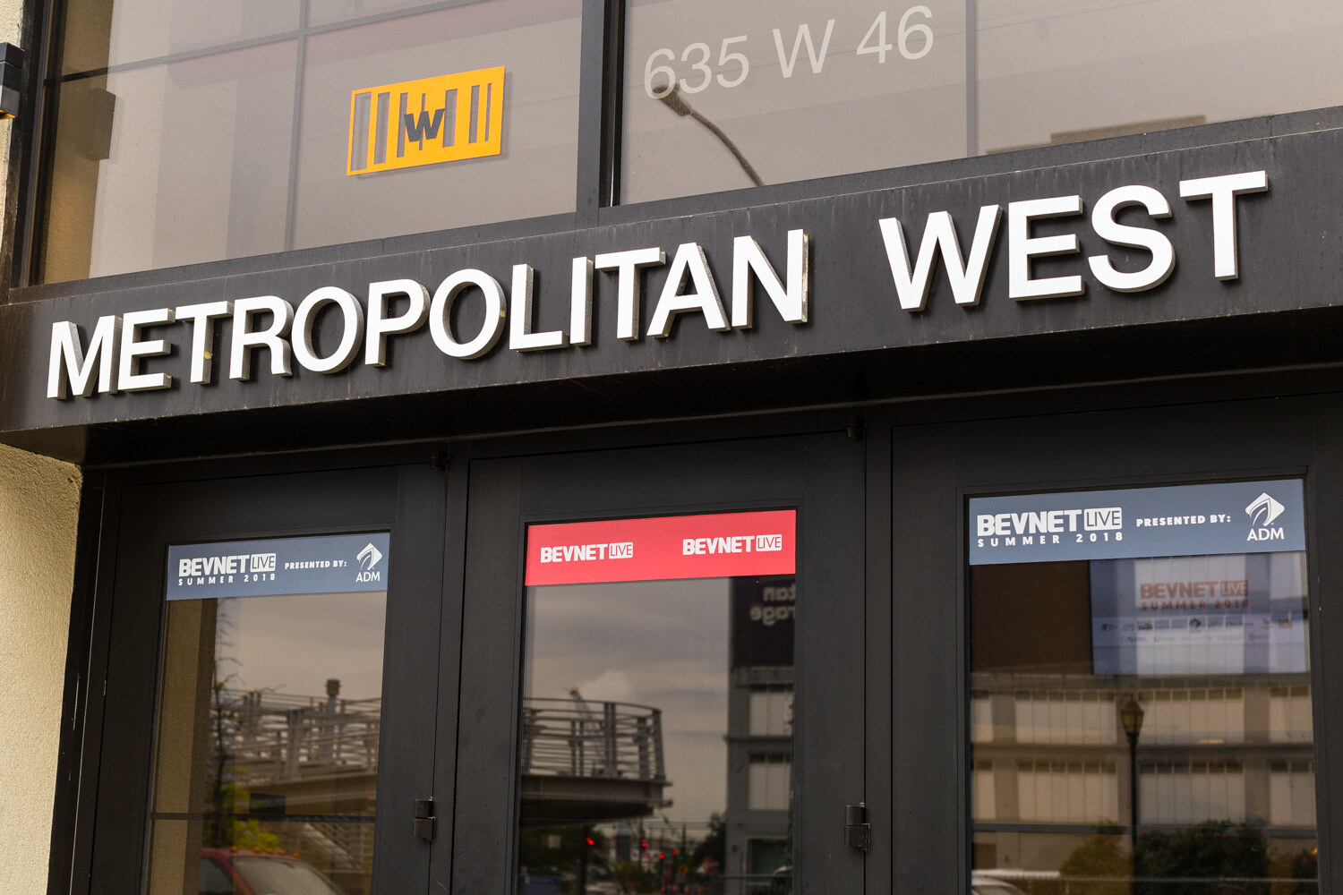 Black double doors beneath a Metropolitan West sign with BevNET Live Summer 2018 window decals presented by ADM.
