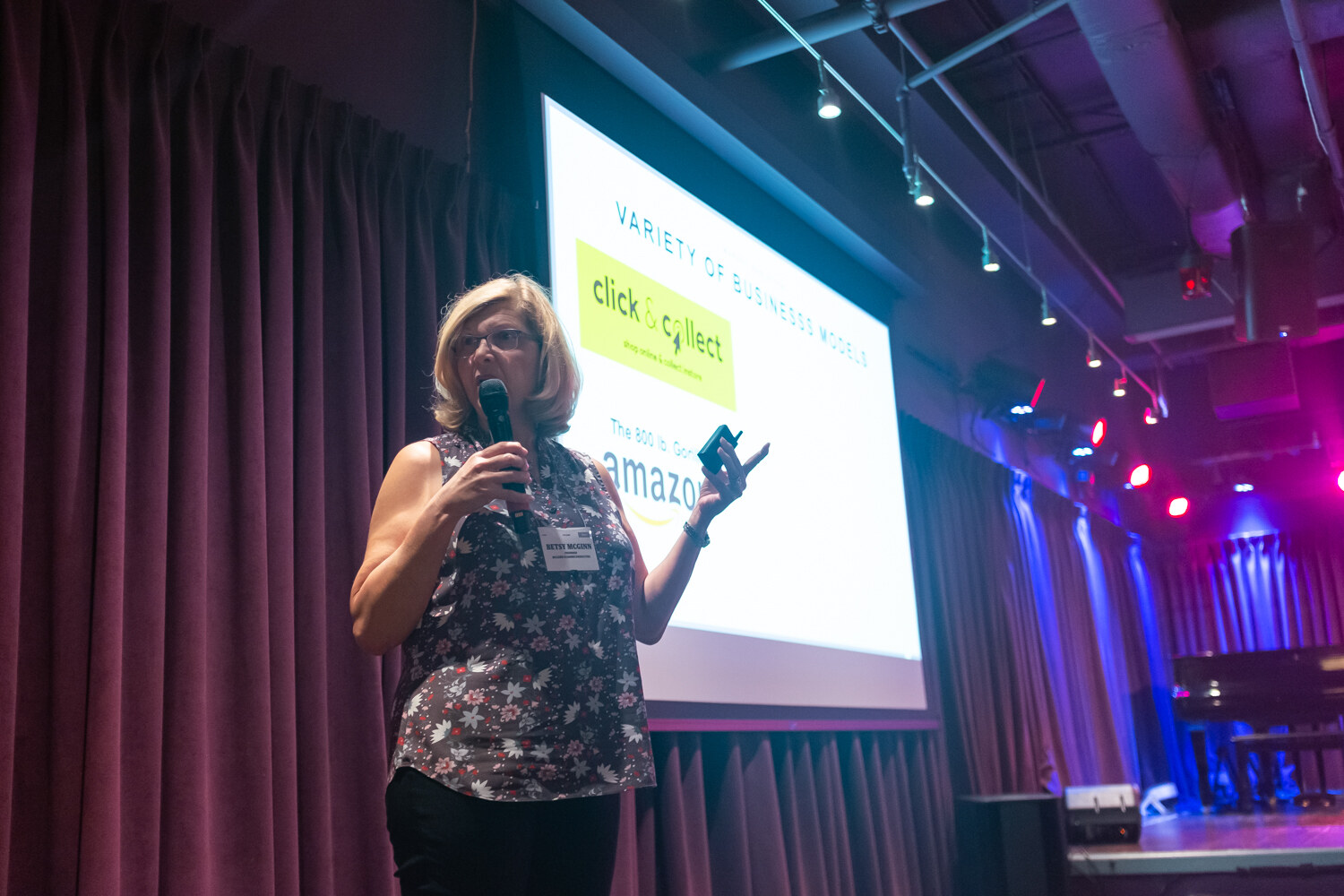 Presenter in a floral sleeveless top speaking beside a screen titled Variety of Business Models.