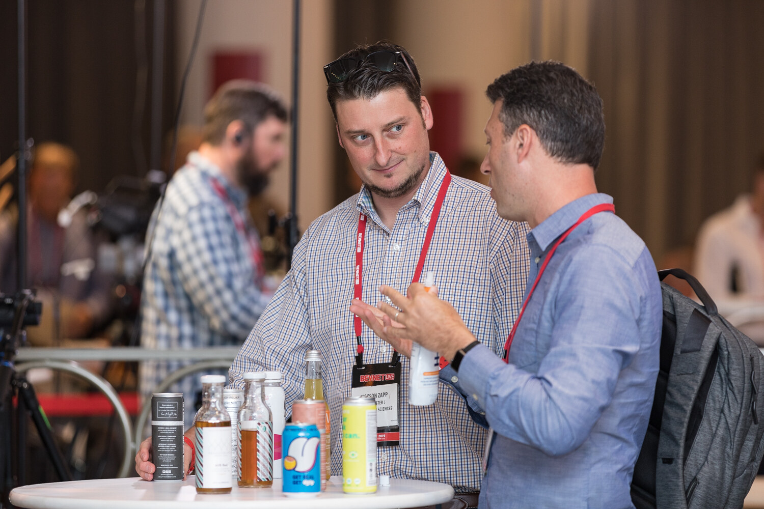 Two attendees talking at a high table with bottled beverages in front of them.