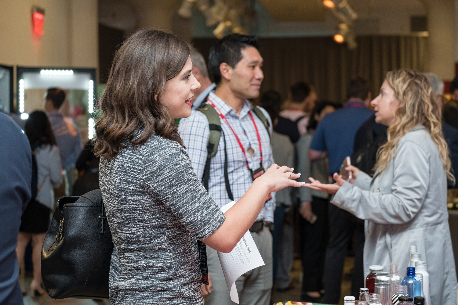Smiling woman talking with another attendee beside a table of products.