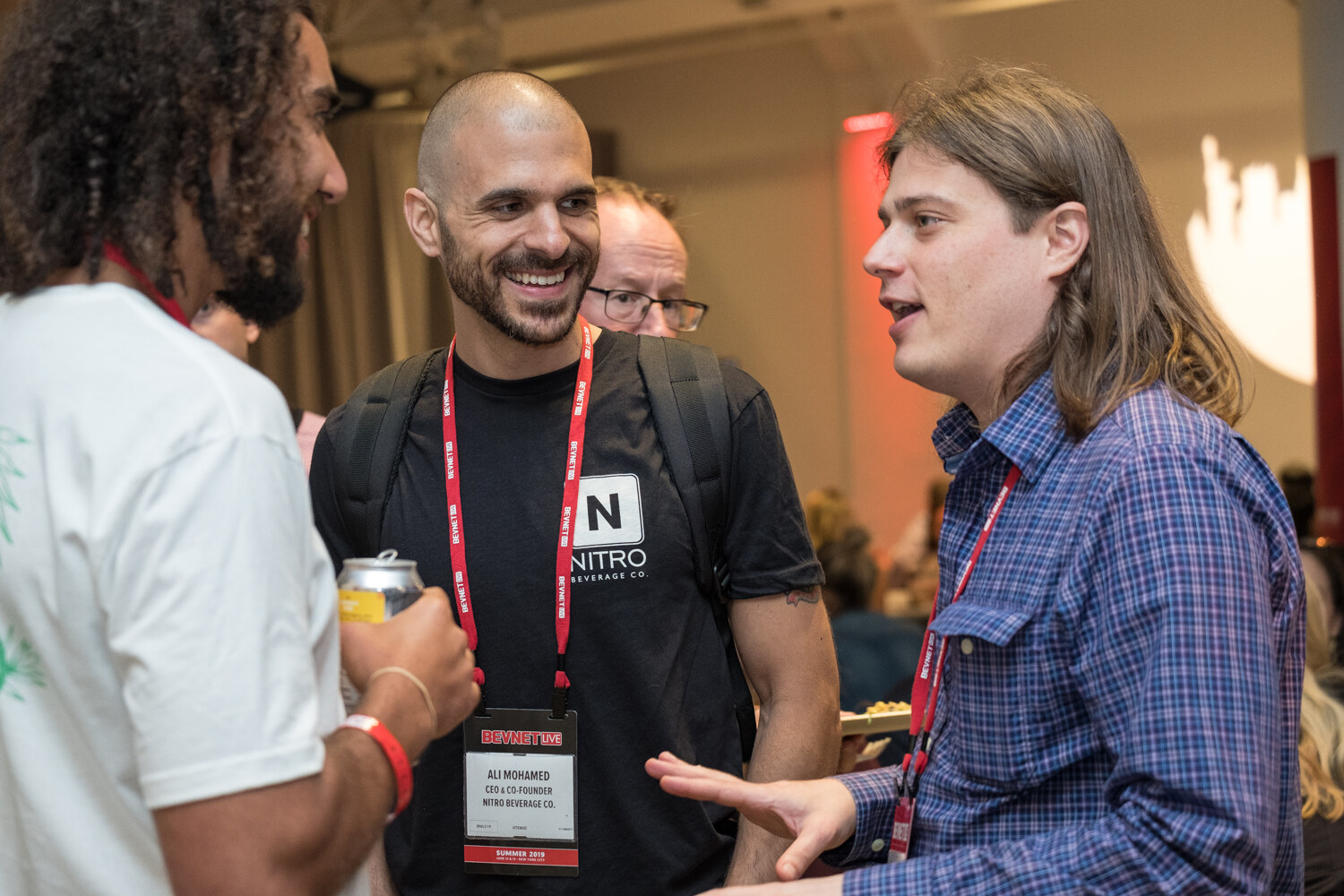 Attendee in a Nitro Beverage Co. t-shirt laughing with two other guests.
