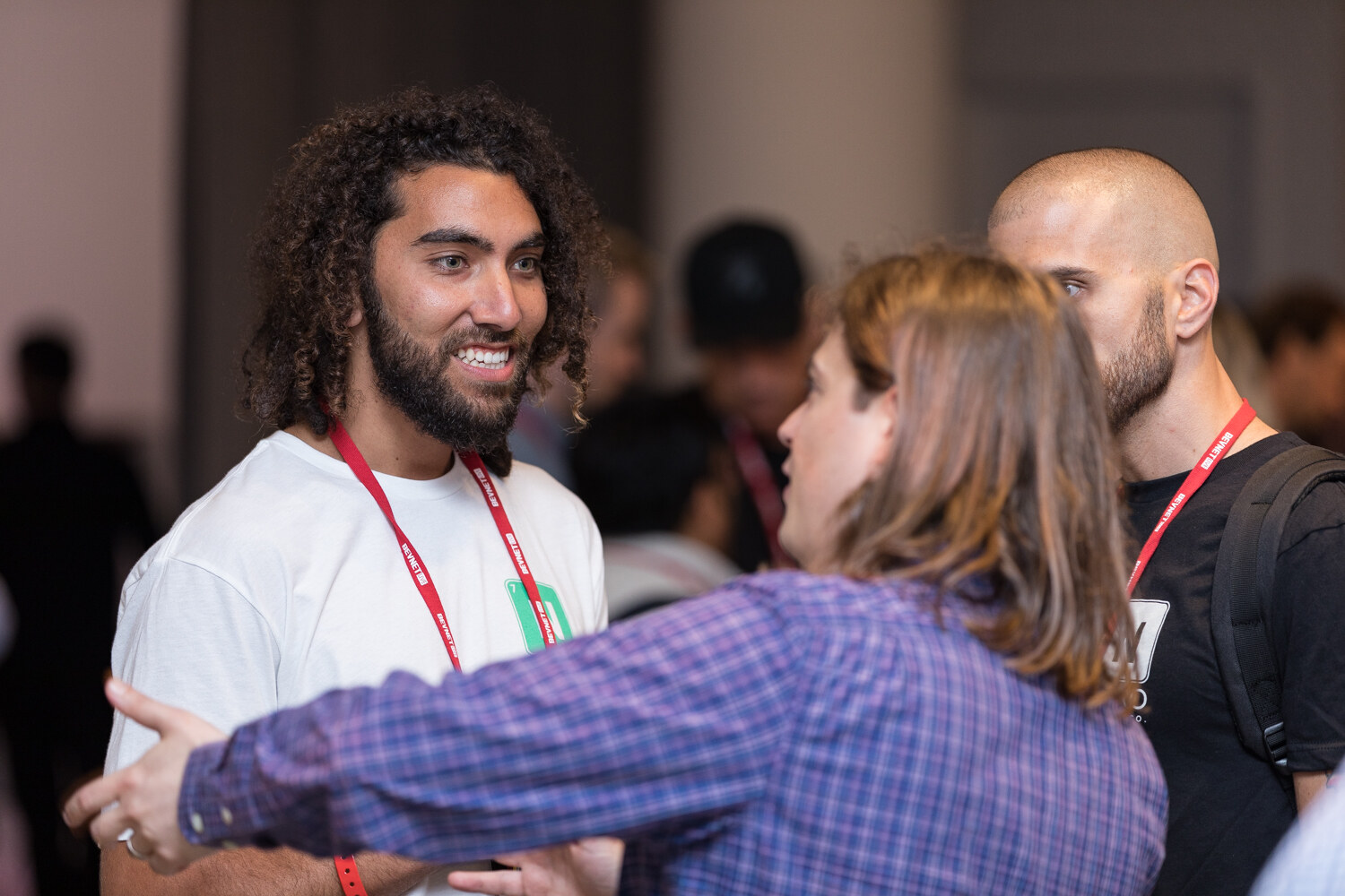 Attendee in a white t-shirt greeting another guest with an embrace.