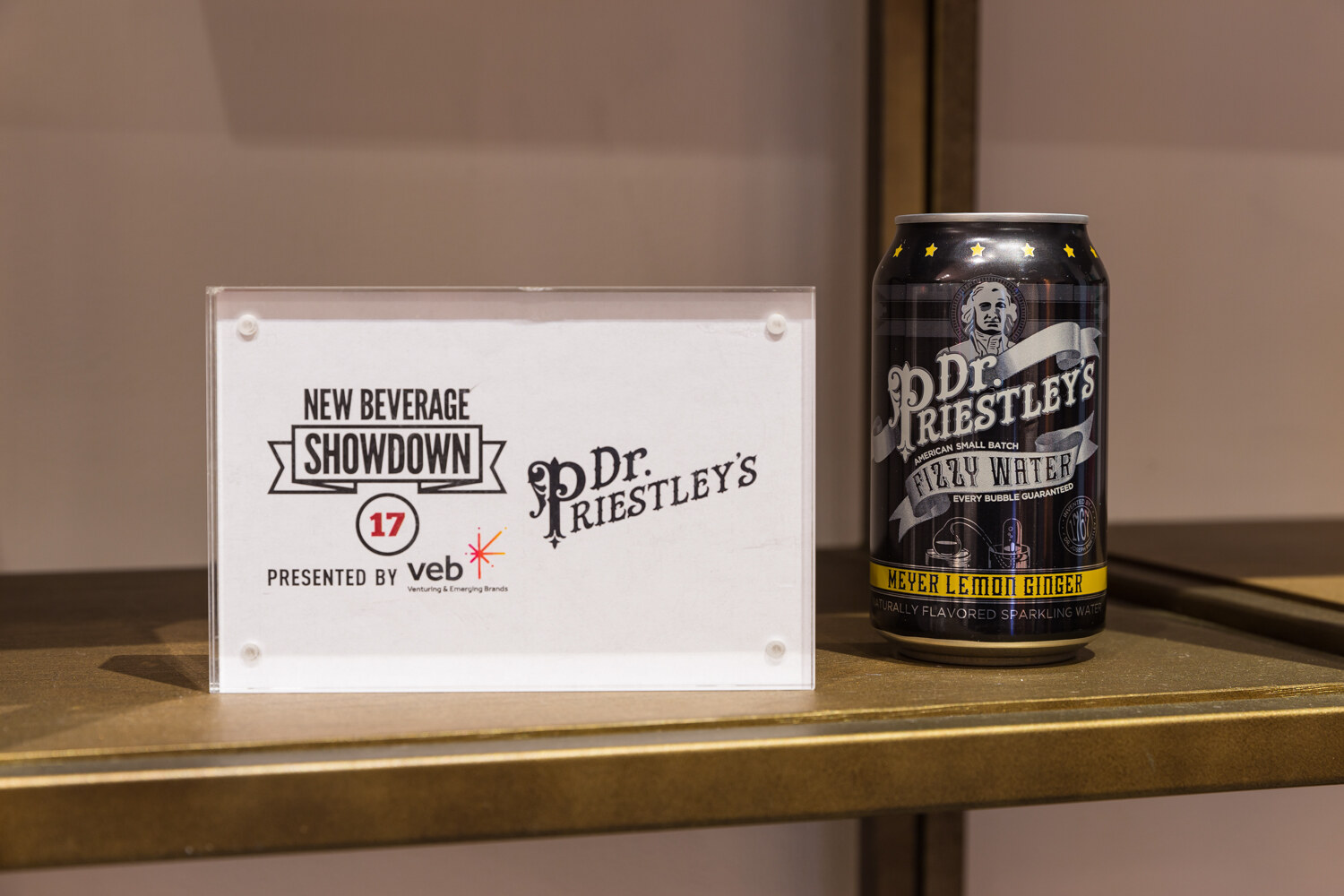 Dr. Priestley's Very Water can displayed on a shelf beside a New Beverage Showdown sign.