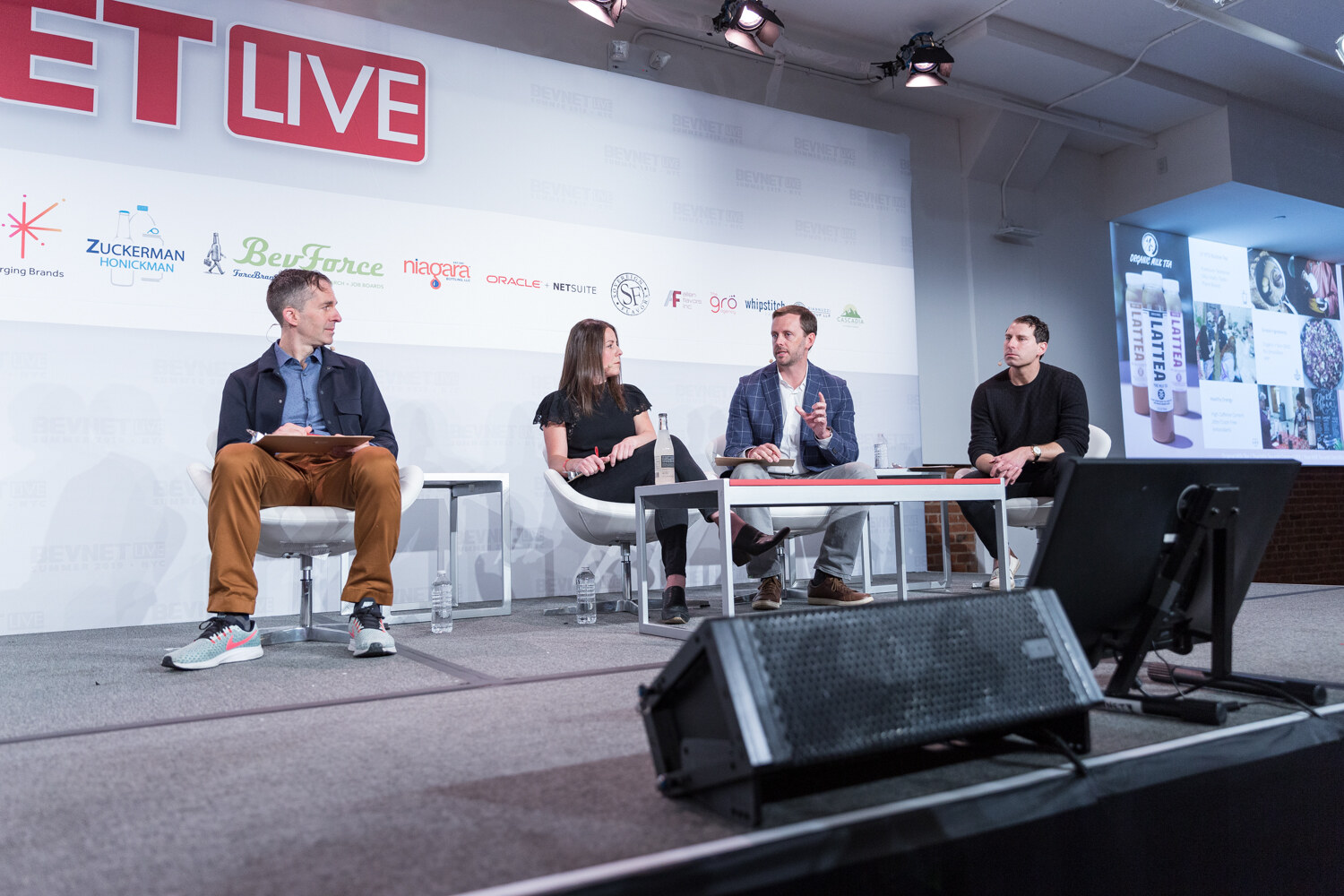 Wide view of four judges seated on stage in front of the BevNET Live backdrop during the semifinal.