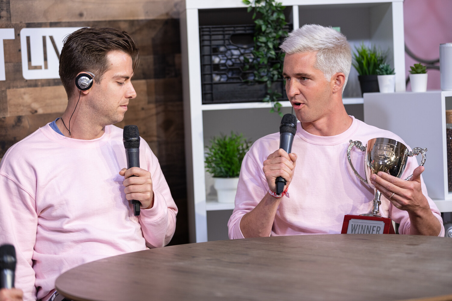 Winner holding the silver trophy and speaking into a microphone at the livestream set.