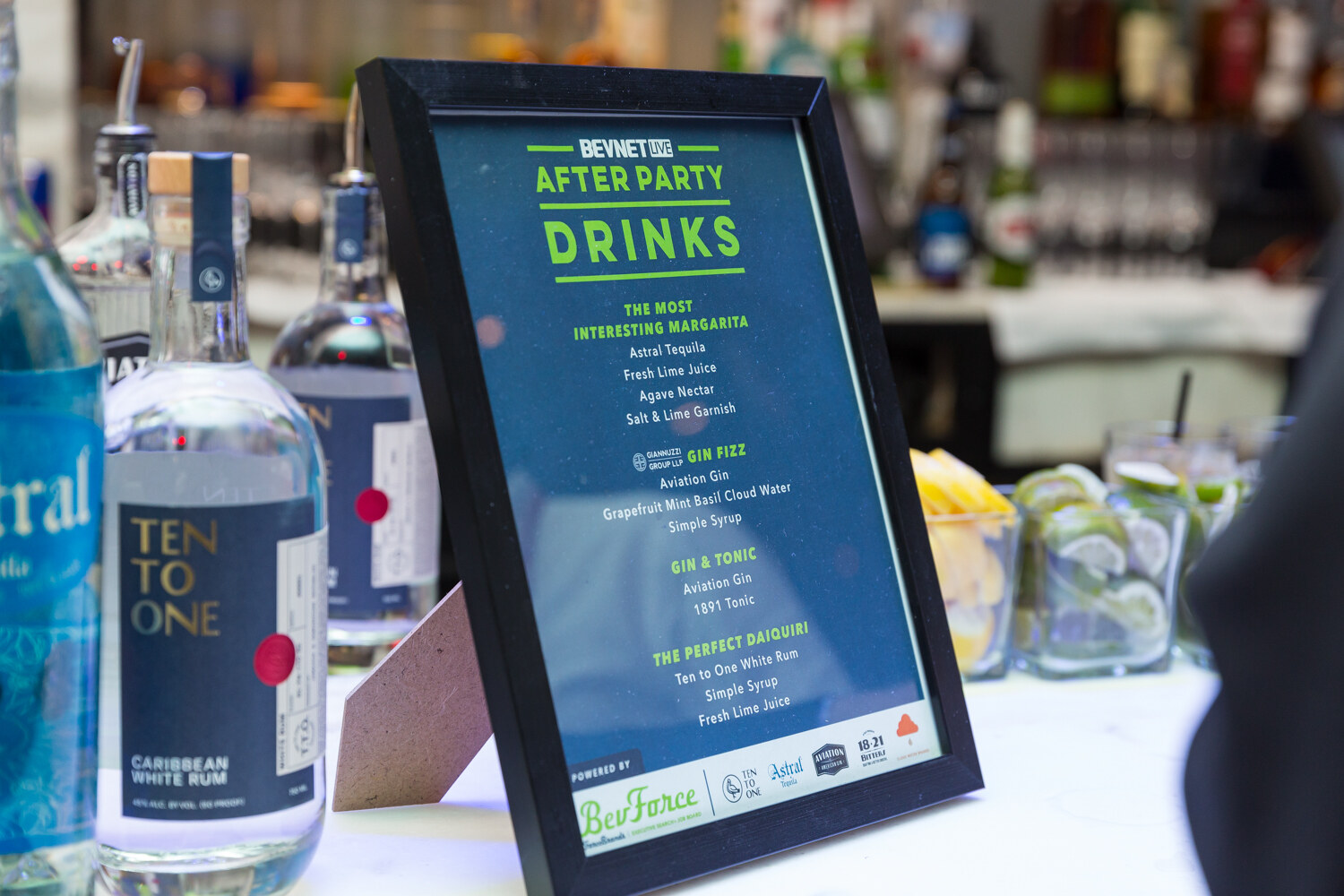 Framed After Party drinks menu beside bottles of Ten to One Caribbean white rum on the bar.