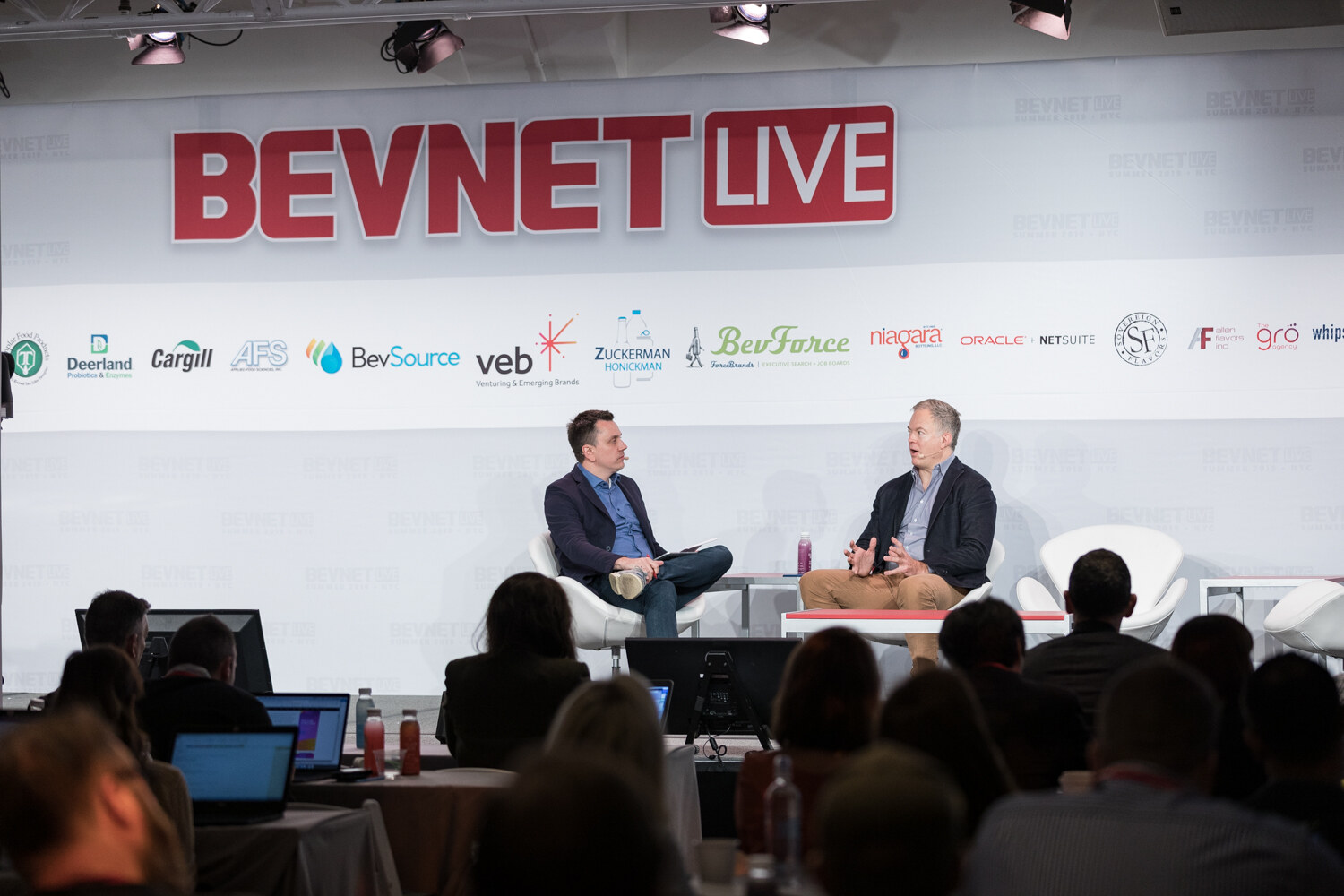 Wide view of the fireside chat on the BevNET Live stage with the audience in the foreground.