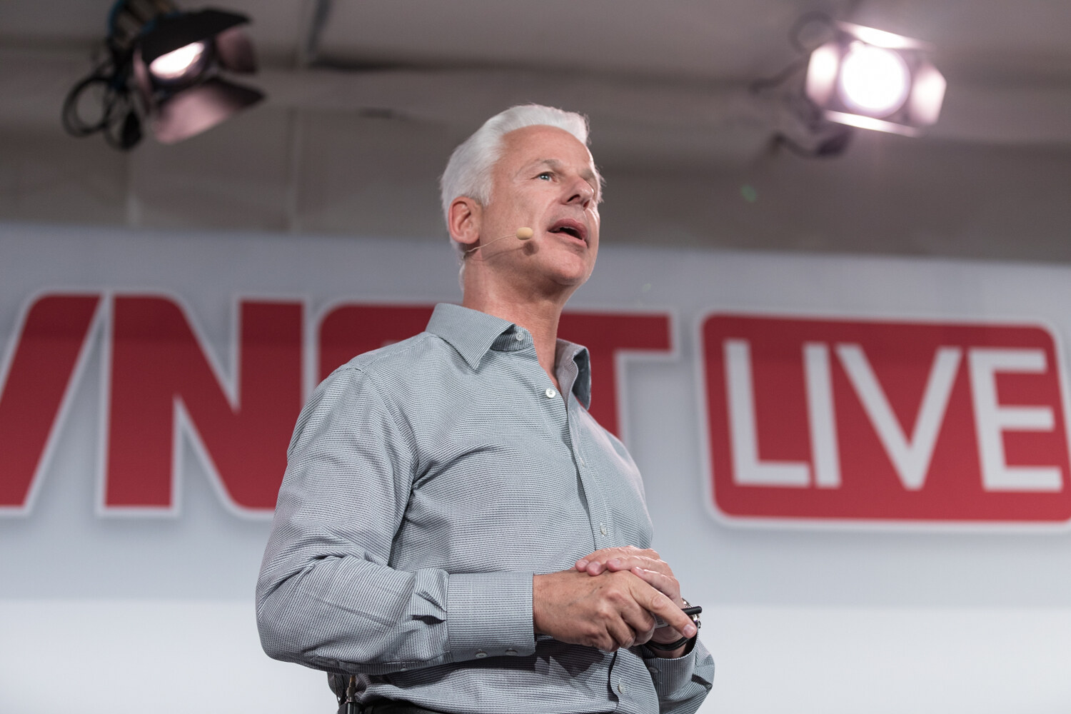 Speaker with clasped hands in front of the BevNET Live sign.
