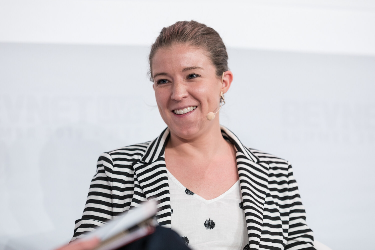 Close view of a smiling woman in a striped blazer during the seated conversation.