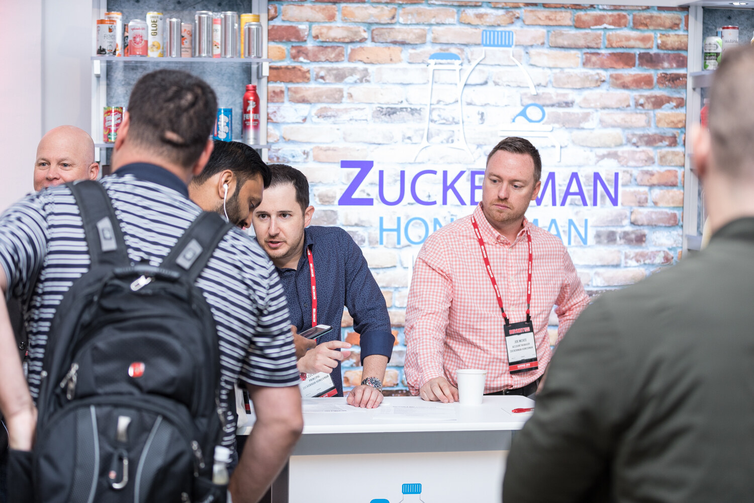 Attendees gathered at the Zuckerman Honickman booth in front of a brick wall.