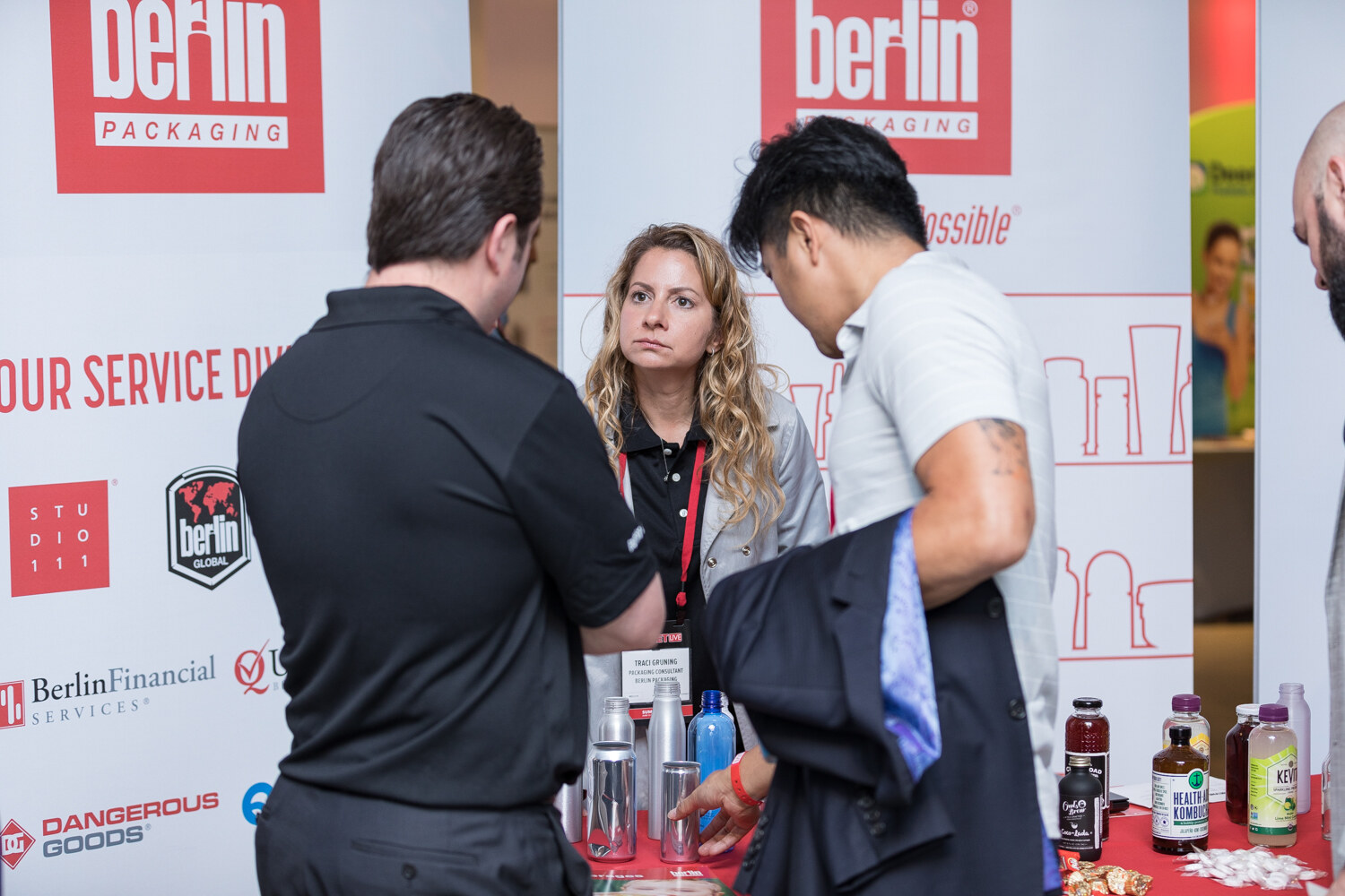 Attendees visiting the Berlin Packaging booth beside bottles of juice.