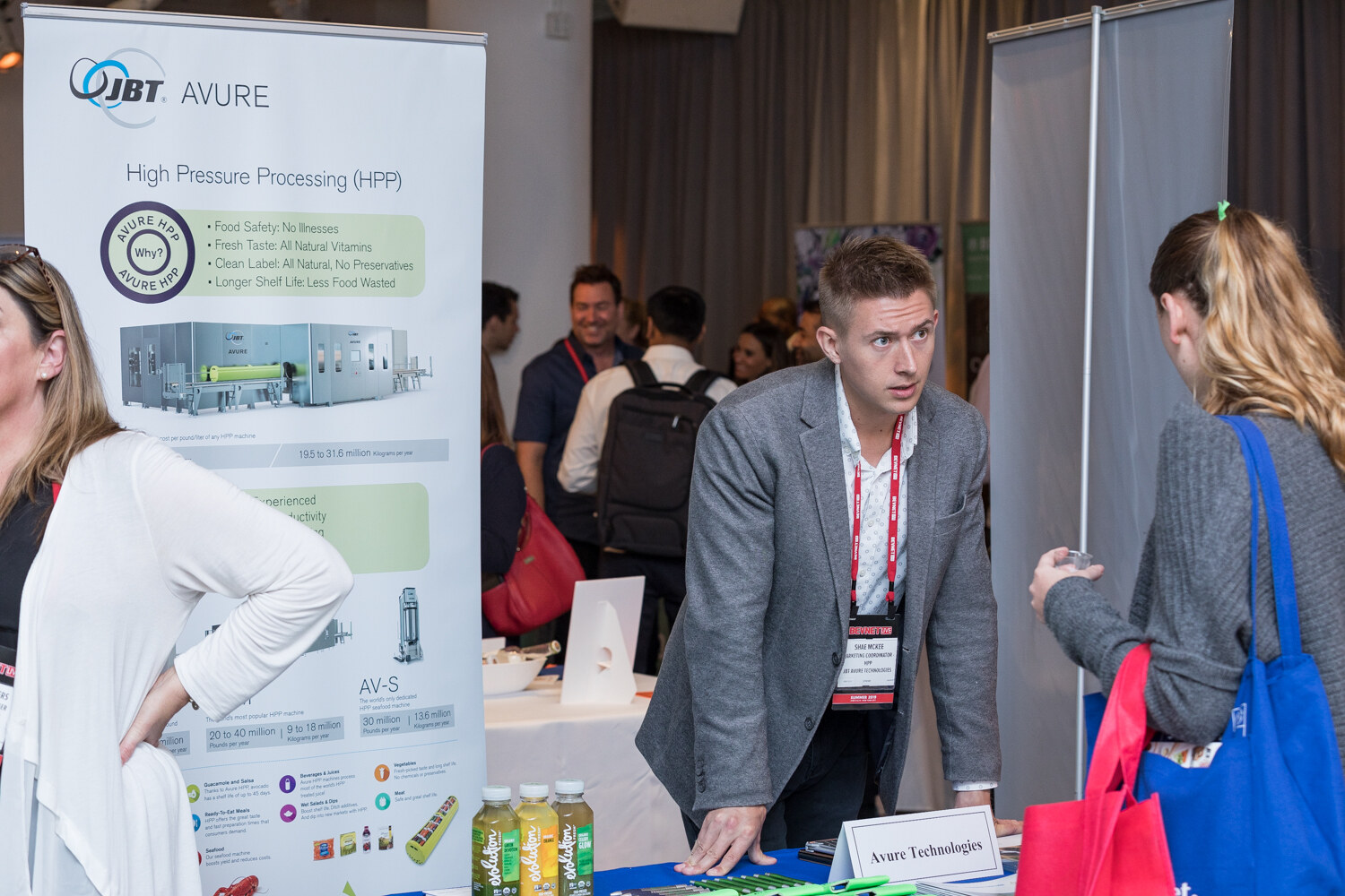 Man in a gray blazer leaning on a table in front of a JBT Avure high pressure processing banner.