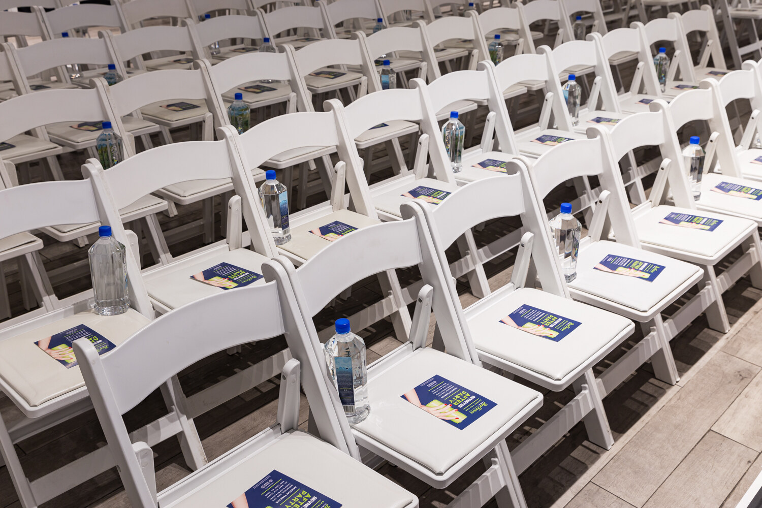 Rows of white chairs set with water bottles and After Party flyers before the sessions.