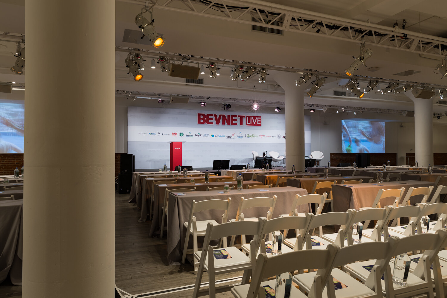 Main session room set with draped tables and white chairs facing the stage before doors opened.