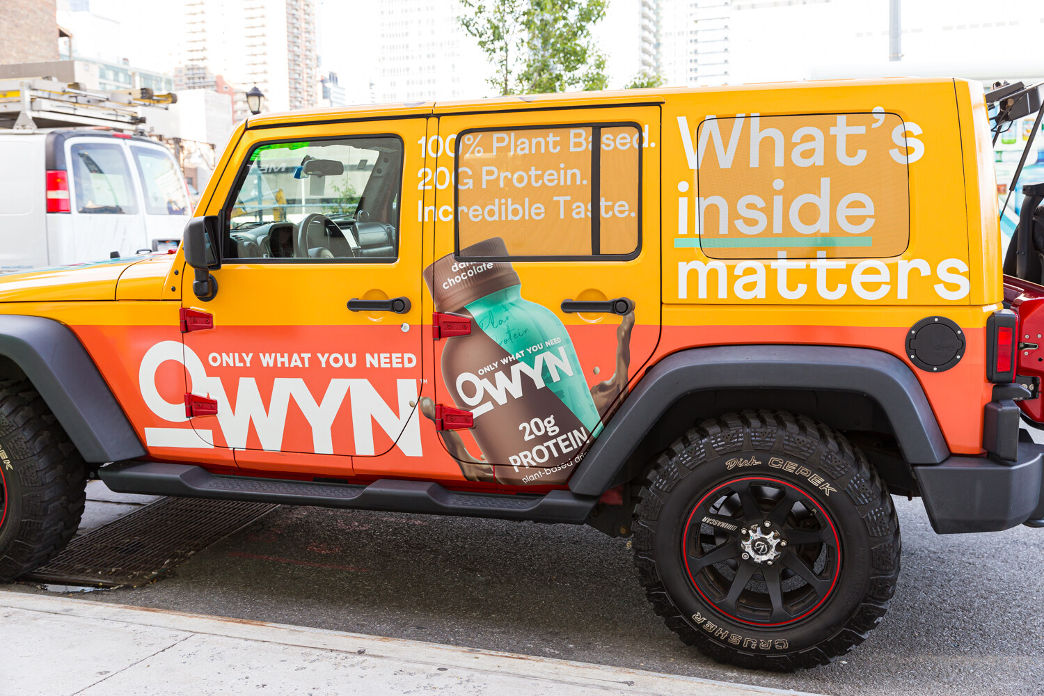 Orange OWYN Jeep wrapped in What's inside matters graphics parked outside the venue.