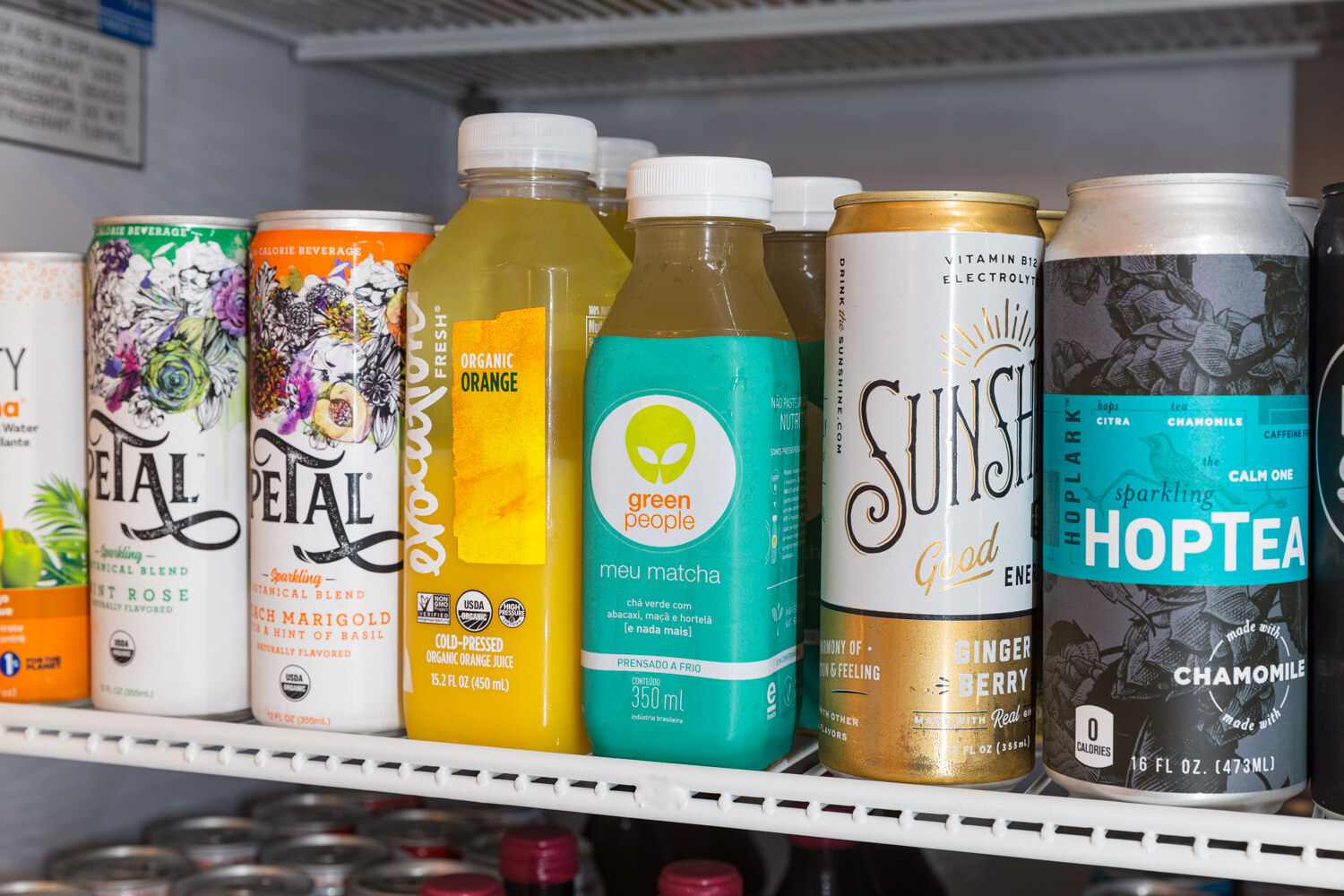 Close view of cooler shelves holding Petal, Green People, Sunshine and Hoptea beverages.