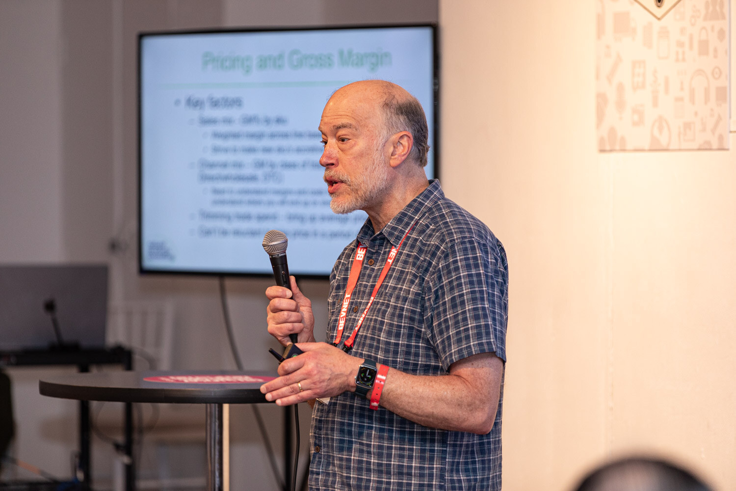 A man with a microphone speaks in front of a screen titled Pricing and Gross Margin.