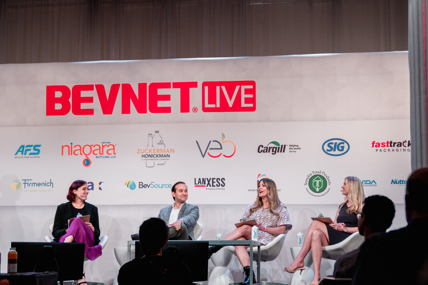 Four people seated on a stage under the BevNET Live sign, with attendees' heads in the foreground.