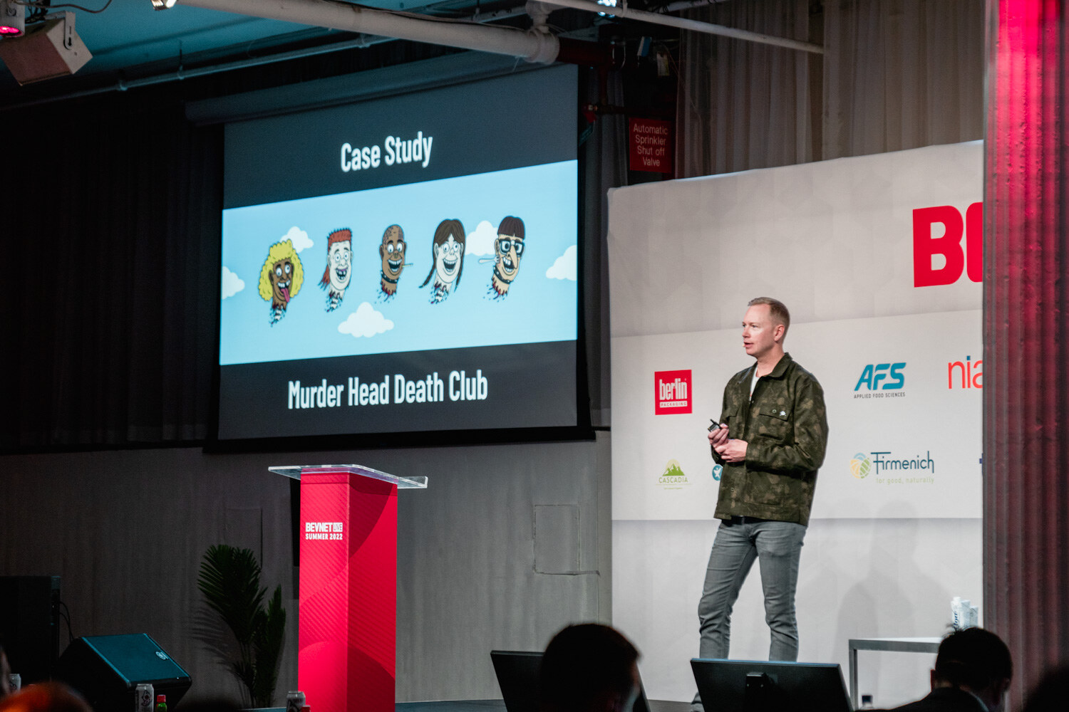 A man in a green jacket stands at the right of a screen that reads Case Study Murder Head Death Club with five cartoon heads.