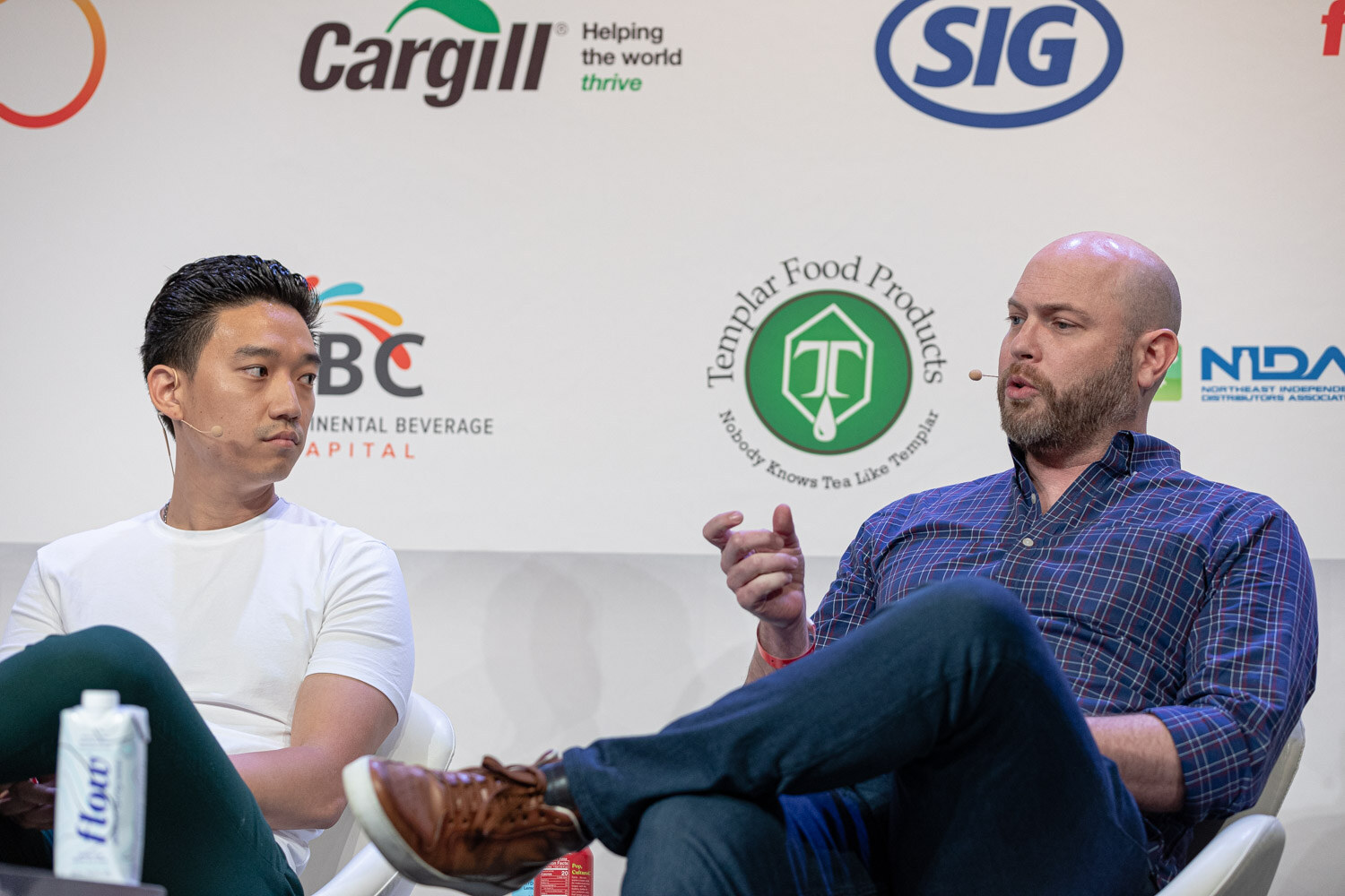 A man in a white t-shirt listens while a bearded man in a plaid shirt gestures, with Templar and IBC logos behind them.