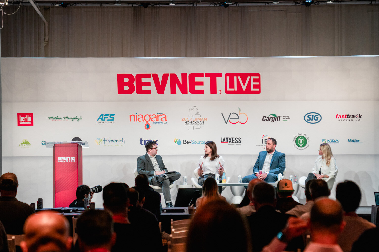 Wide view of four people on a stage below a BevNET Live sign and sponsor logos, with the audience seated in the foreground.