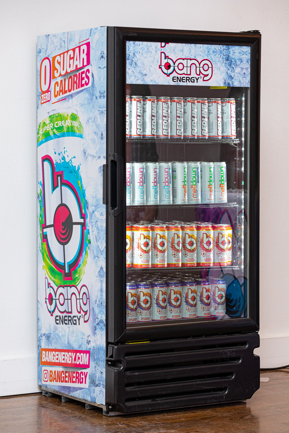 A glass-door cooler with Bang Energy graphics and rows of cans of Bang drinks.