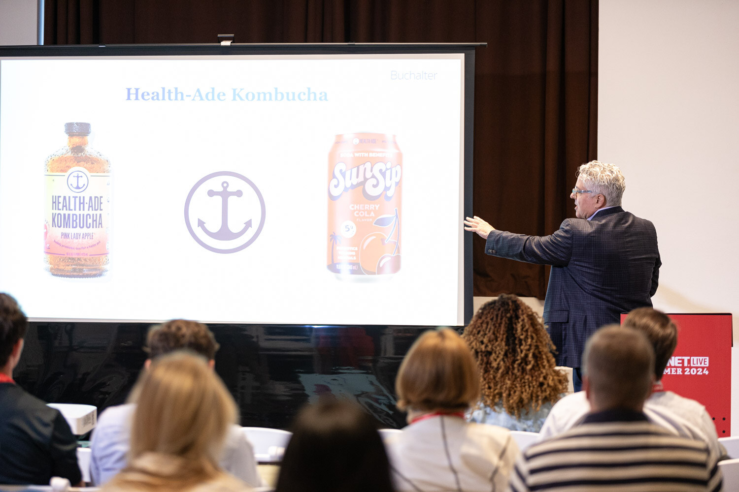 Presenter gestures toward a Health-Ade Kombucha and SunSip slide during Beverage School.