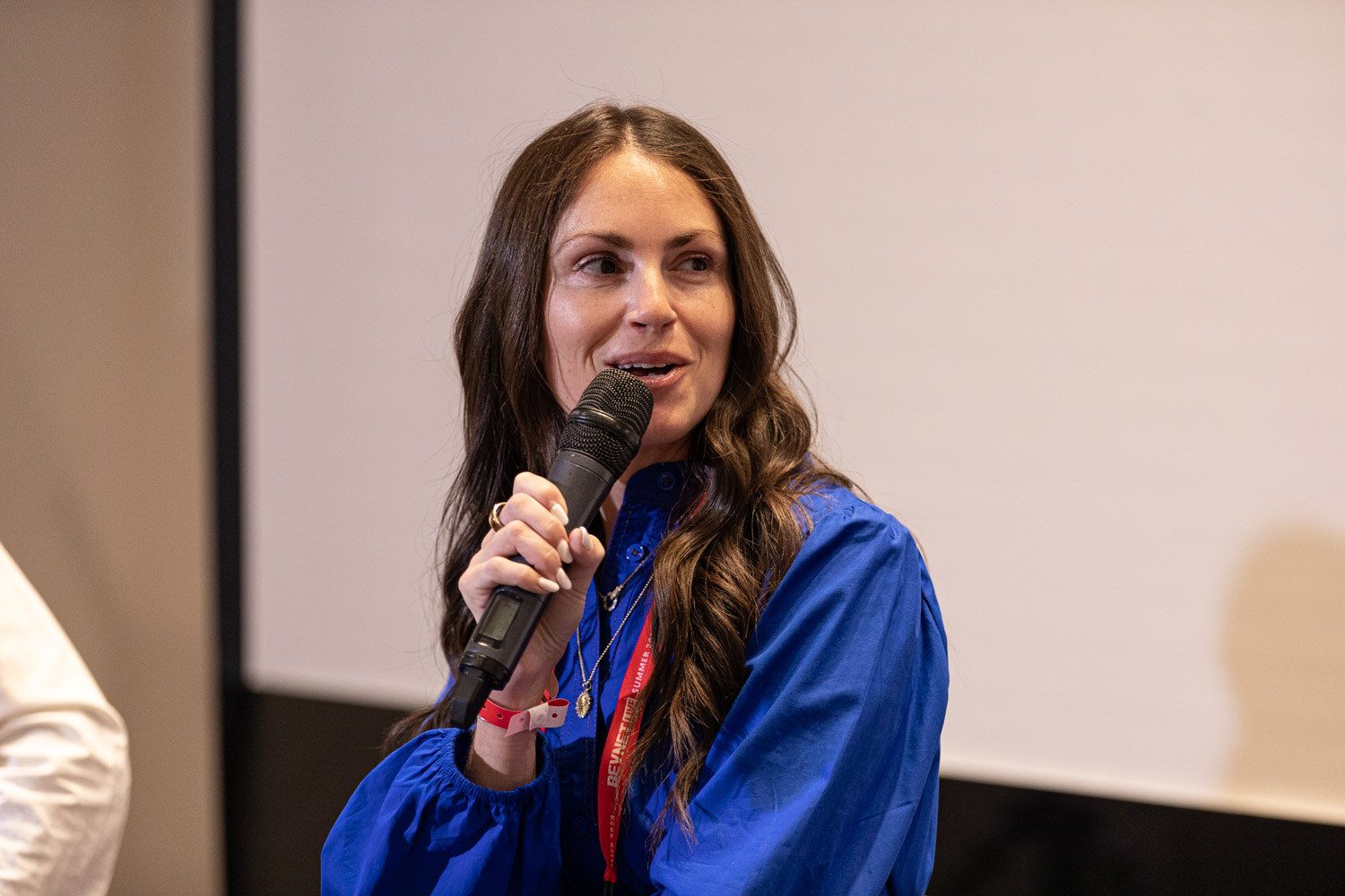 Panelist in a blue dress speaks into a microphone during the Beverage School panel.