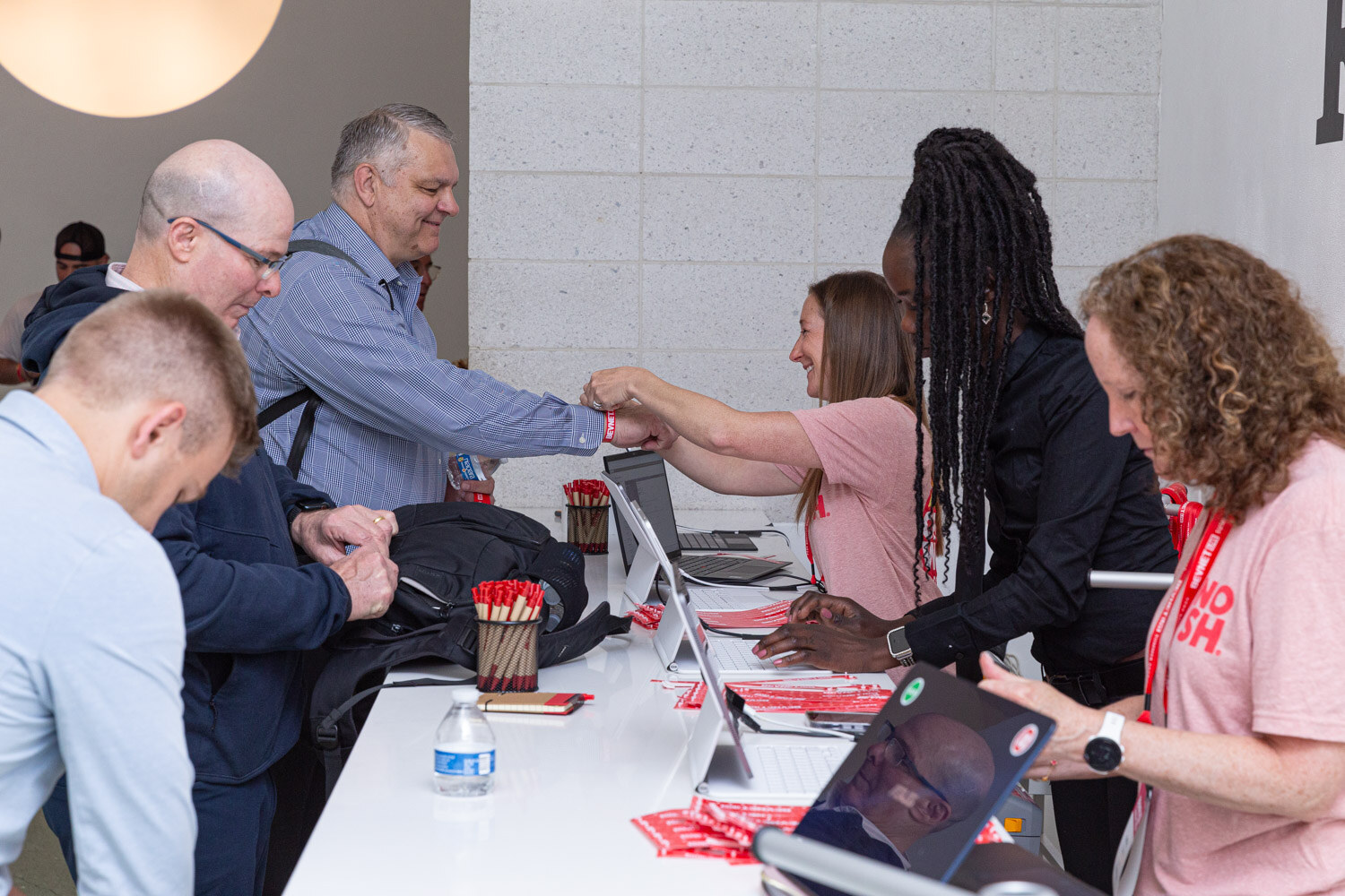 Registration staff greet attendees and hand over badges at the check-in counter.