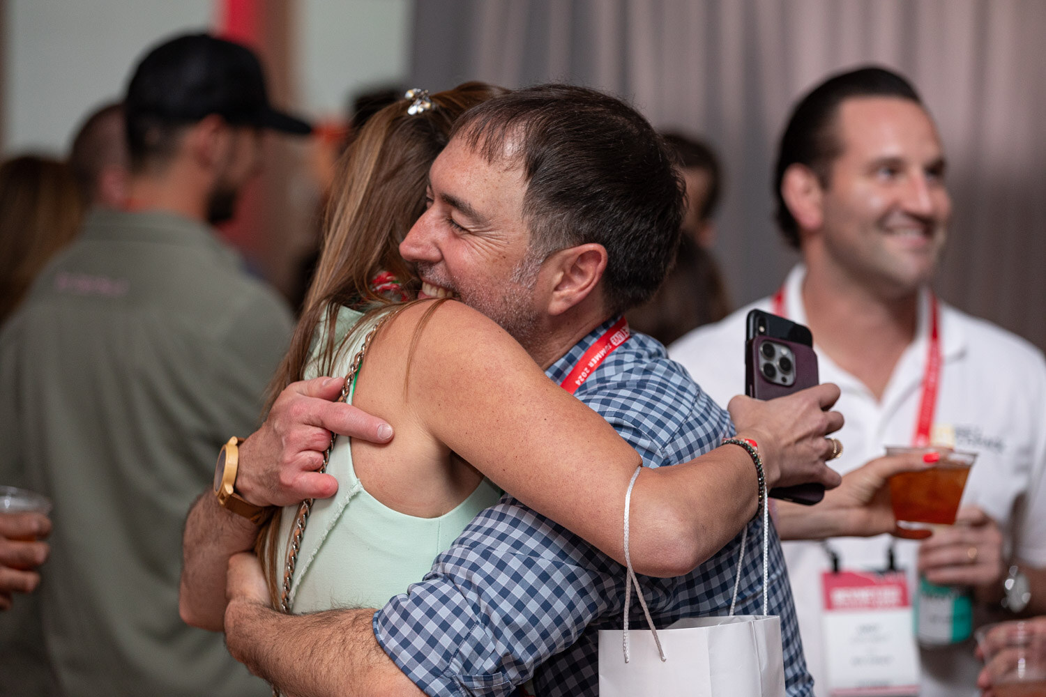Two attendees hug during the happy hour.