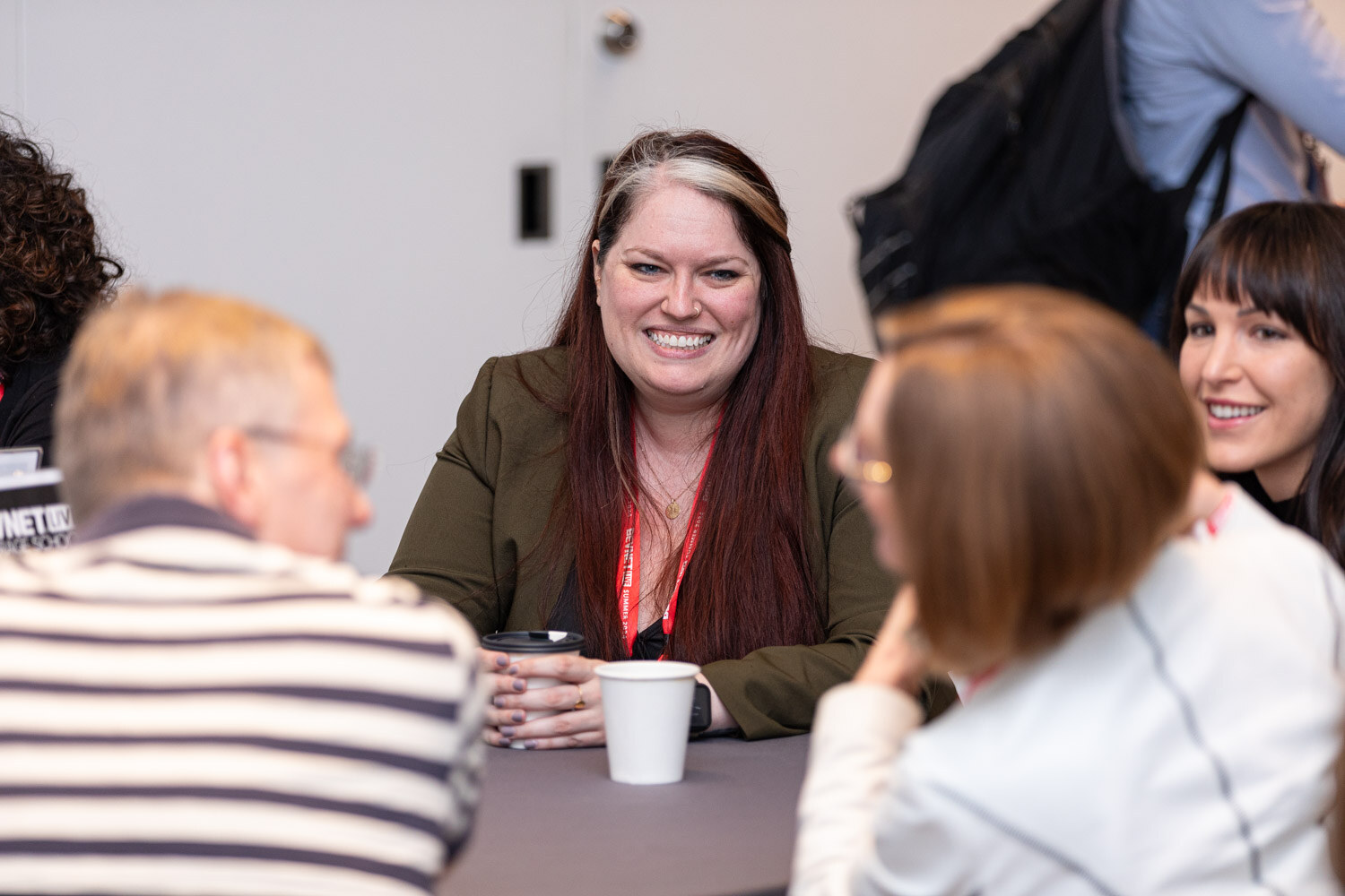Attendee in a green blazer smiles while networking.
