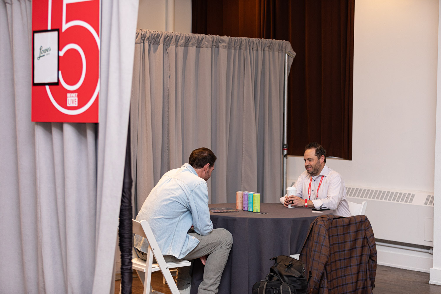 Two attendees meet at a round table with sample cans during One-to-Ones.