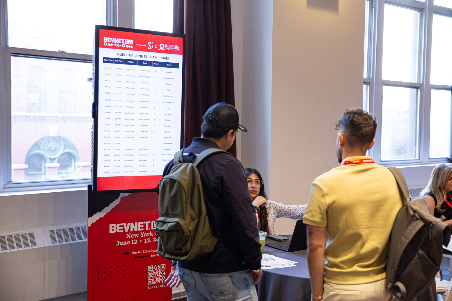 Attendees check the One-to-Ones schedule board in the meeting room.