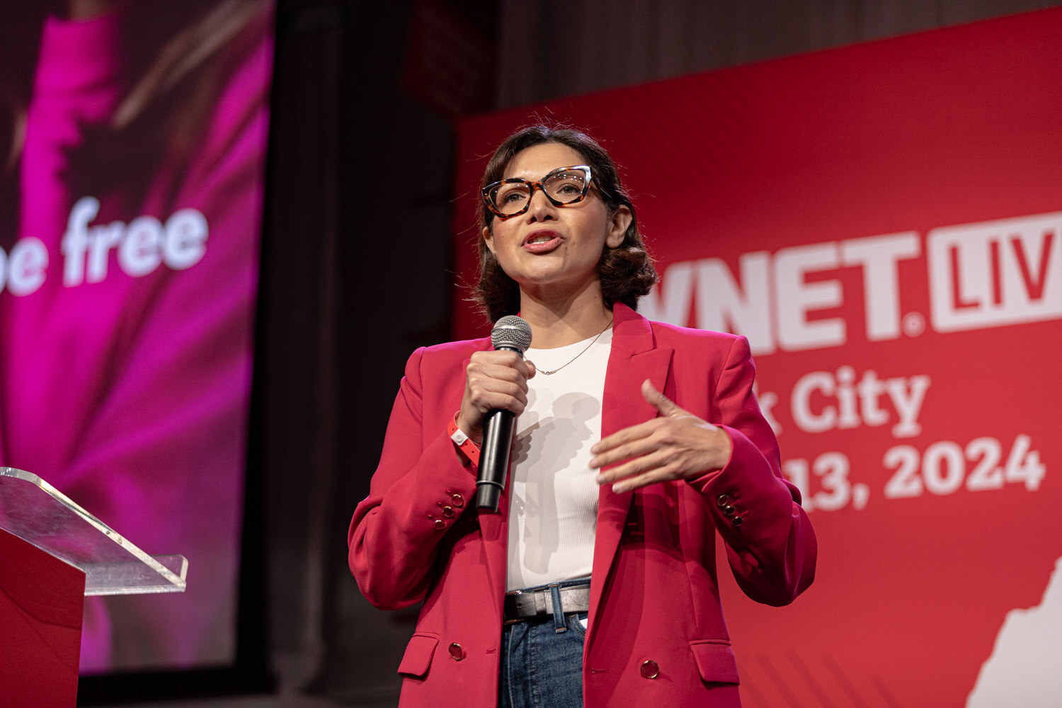 Contestant in a red blazer presents in front of a be free slide.