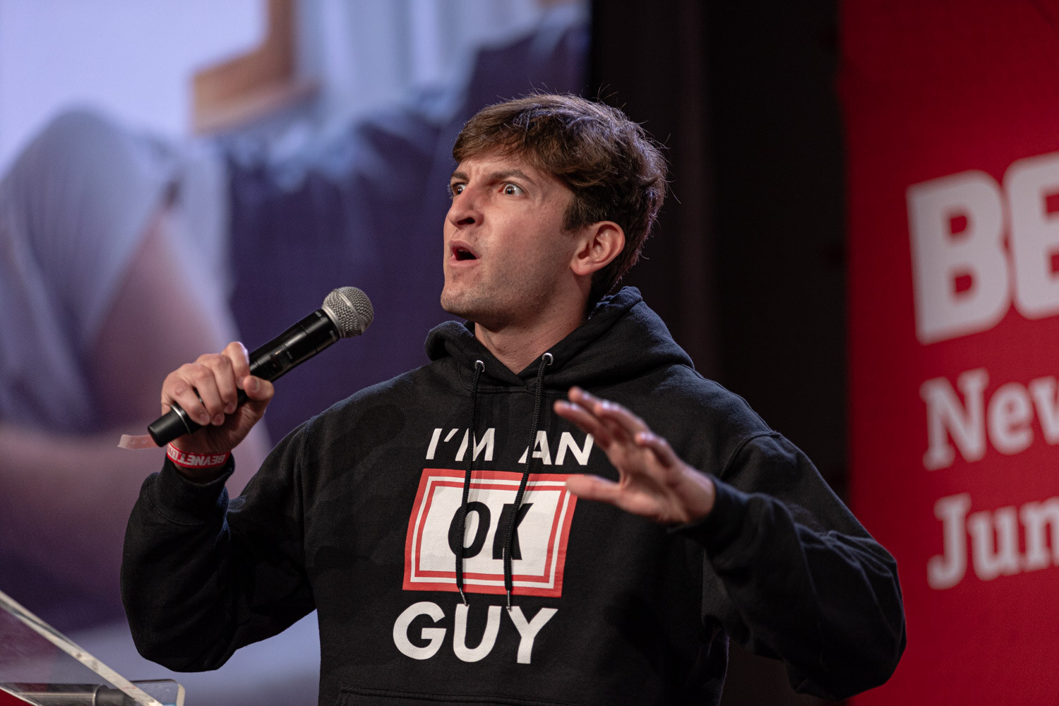 Finalist in an I'm an OK Guy hoodie gestures with both hands.