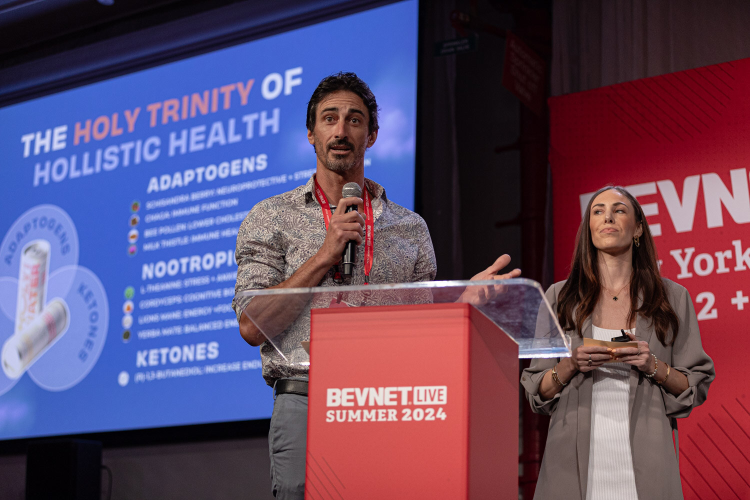 Finalist in a patterned shirt presents beside a Holy Trinity of Holistic Health slide.