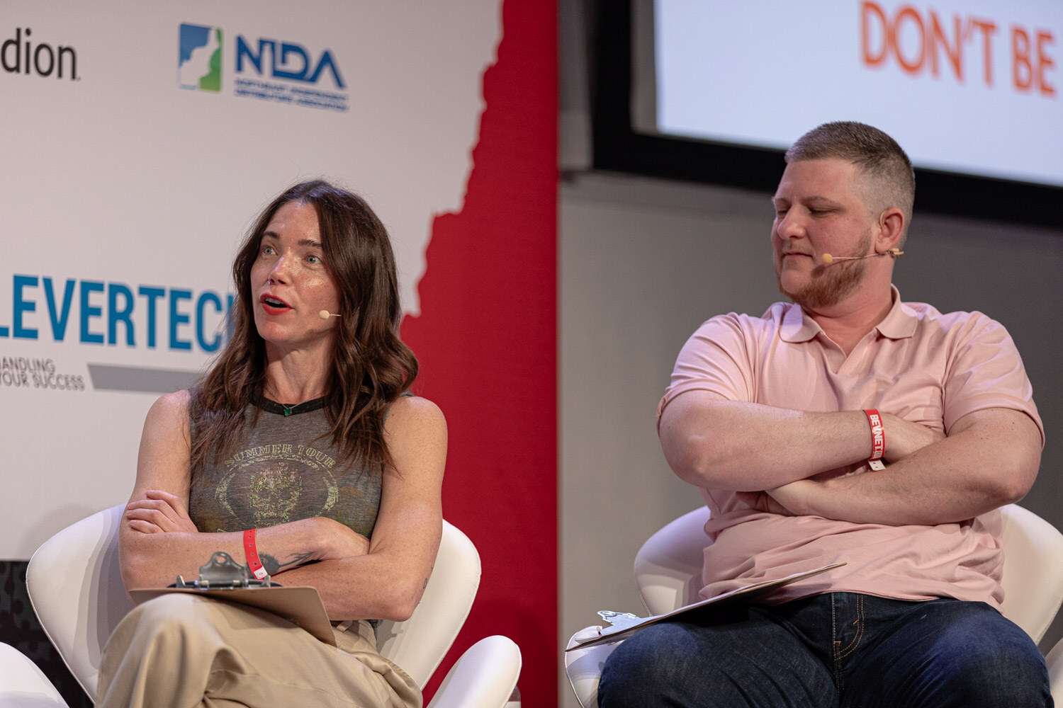 Two judges seated side by side, one in a pink polo with arms crossed.