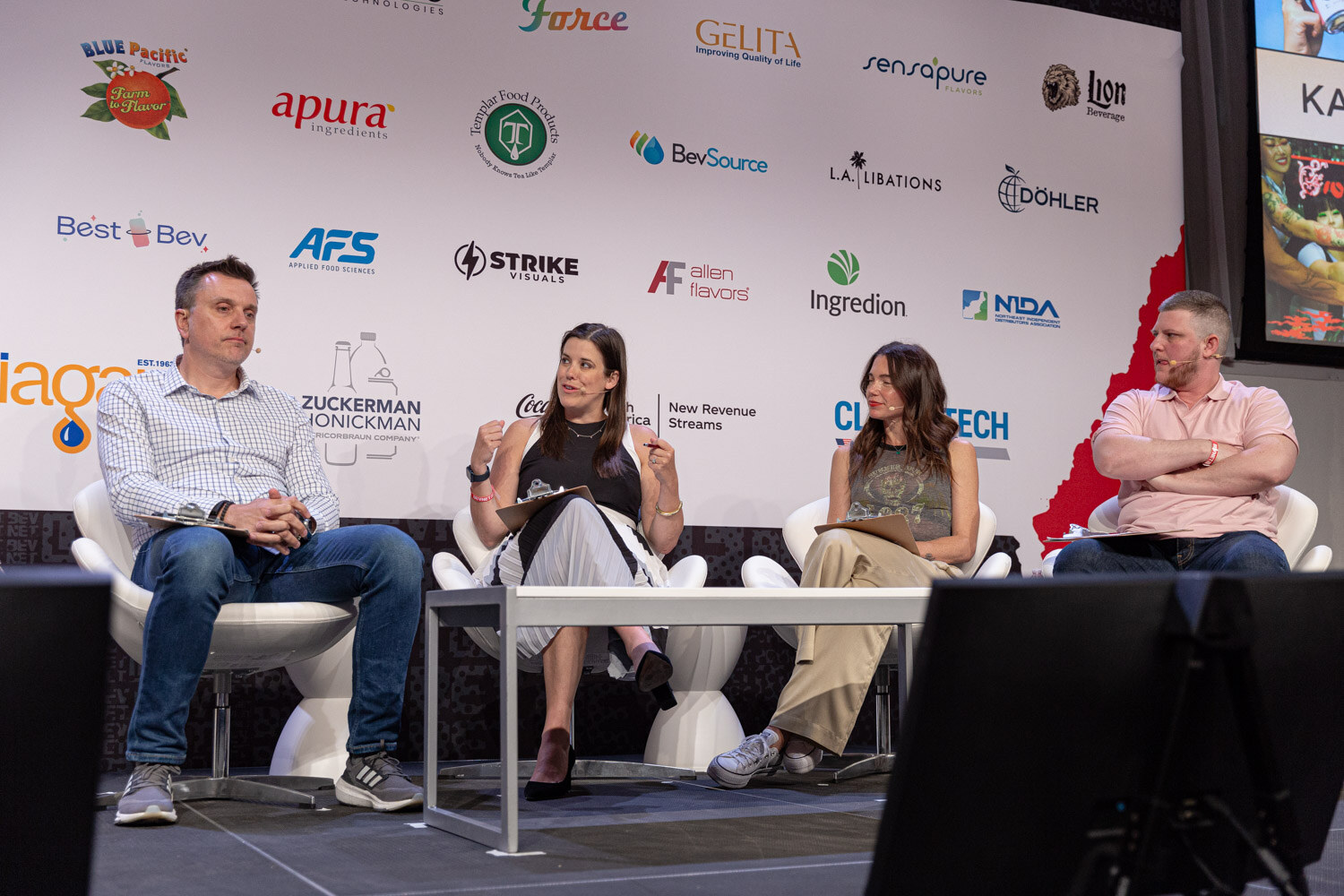 Four judges seated in white chairs on stage during the finals judging.
