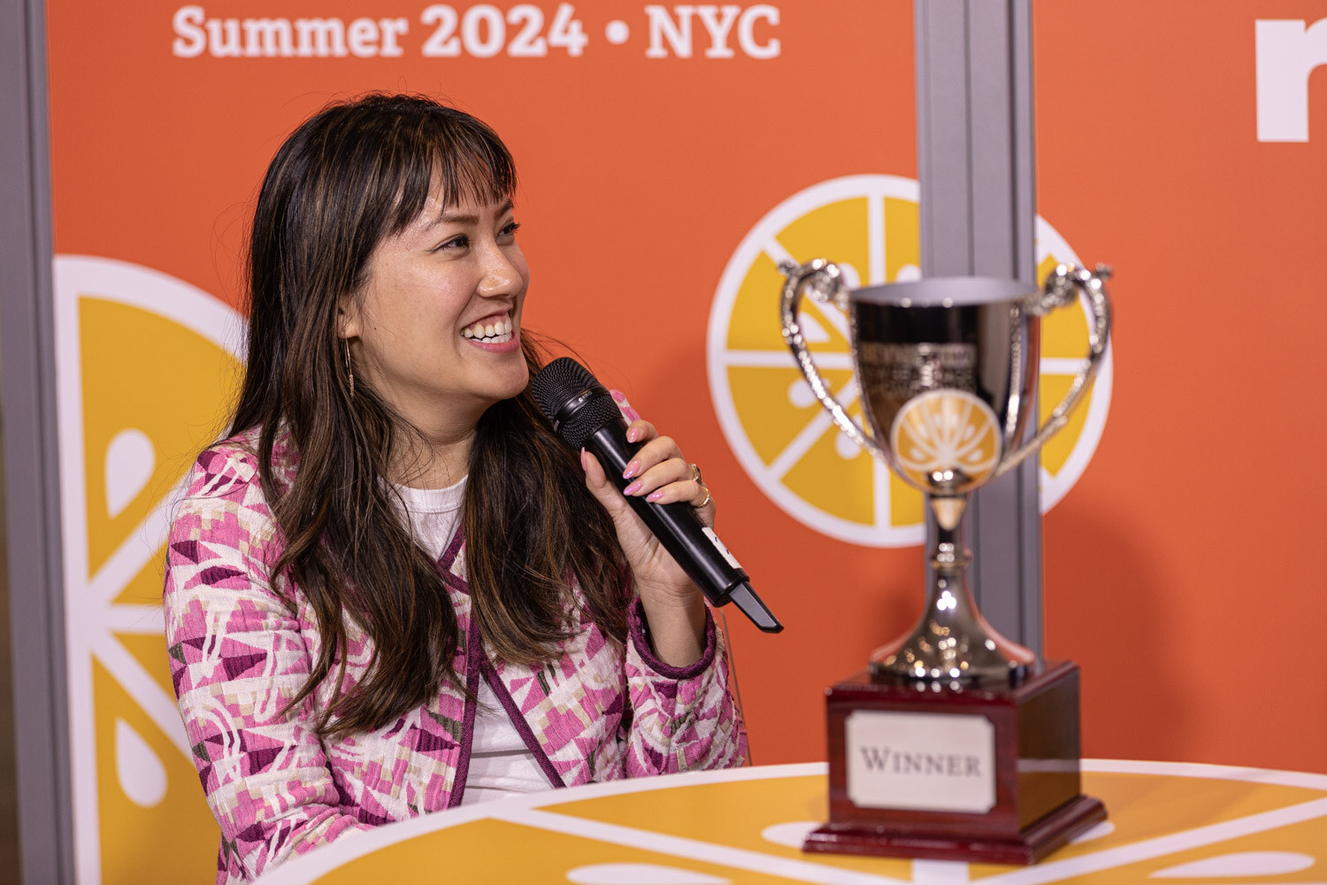 Winner of the New Beverage Showdown speaks into a microphone beside the Winner trophy at the Taste Radio set.