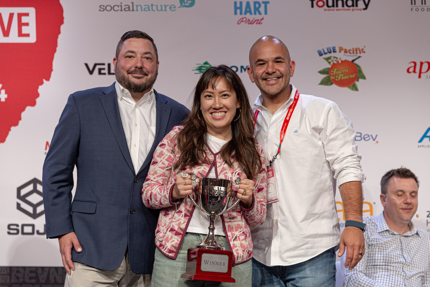 Three people pose with the Winner trophy after the New Beverage Showdown finals.