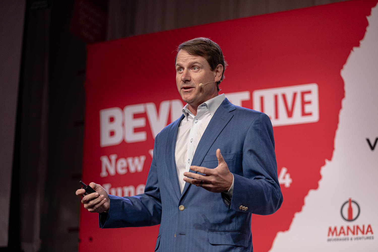 Speaker in a blue blazer presents in front of the BevNET Live New York City backdrop.