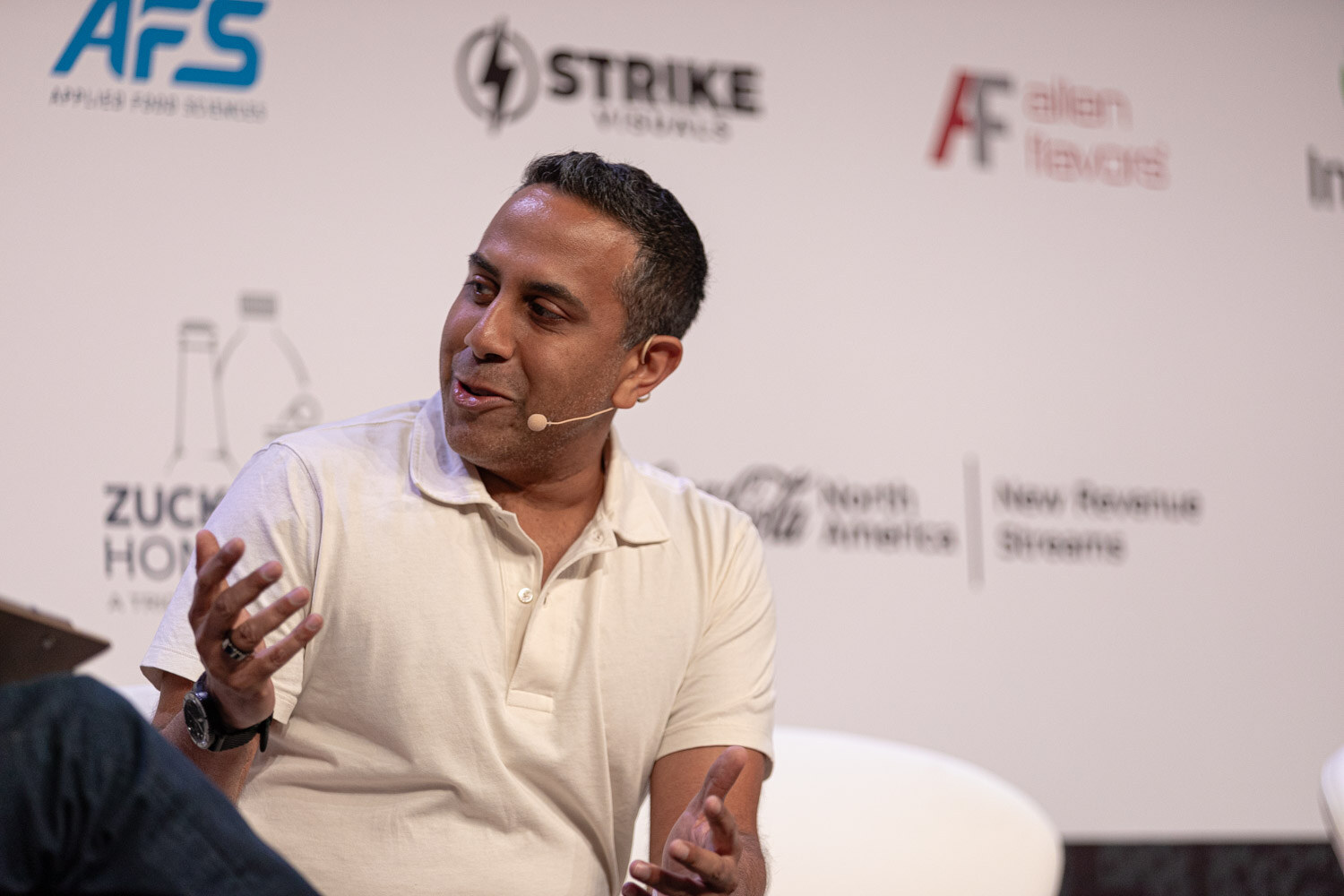 Guest in a cream polo gestures with an open hand while answering a question.