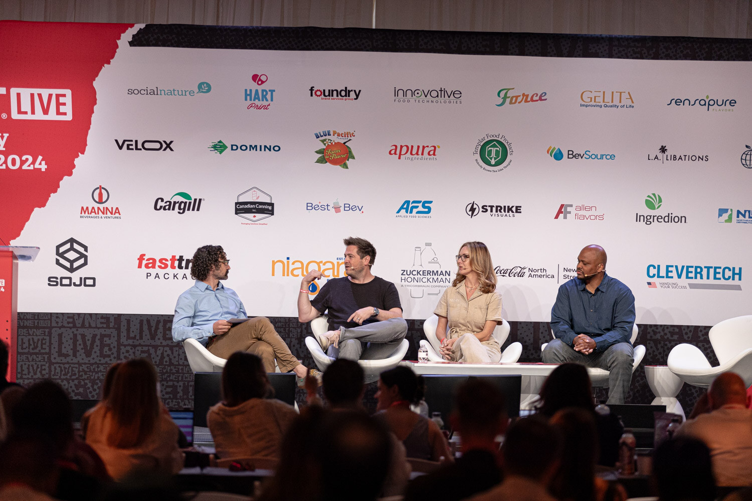Wide view of the moderator and three panelists on stage during Building the Category.