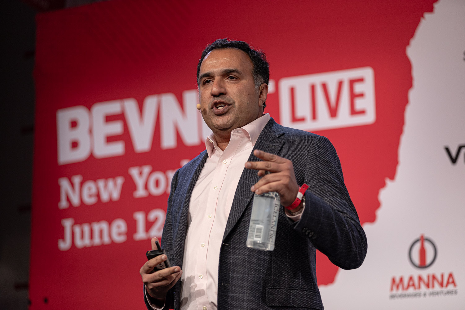 Speaker with a water bottle presents in front of the BevNET Live New York City backdrop.